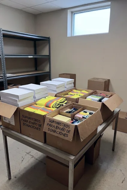 Estantería metálica industrial junto a varias cajas de cartón abiertas llenas de paquetes de hojas de papel blanco y suministros de oficina organizados.