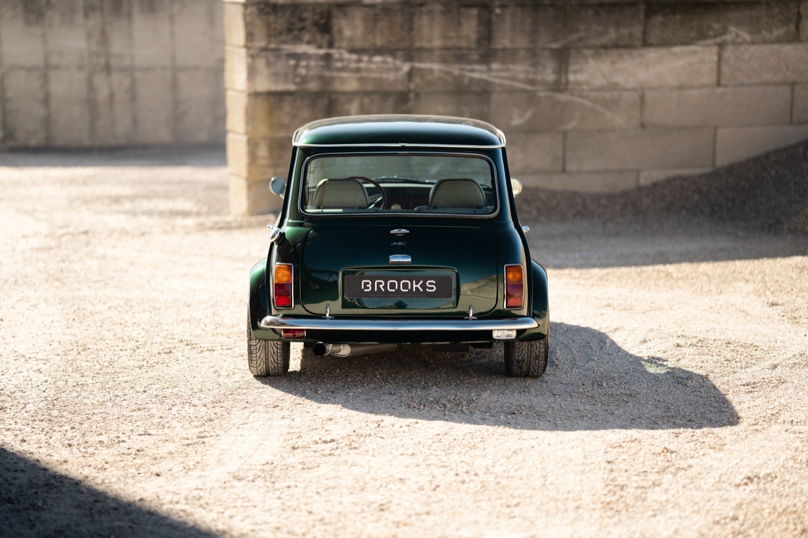 A small, green and black vehicle parked on a sandy surface, with a warm sunset lighting the scene.