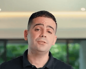 A person on a white shirt and black coat standing at the window indoor of the office