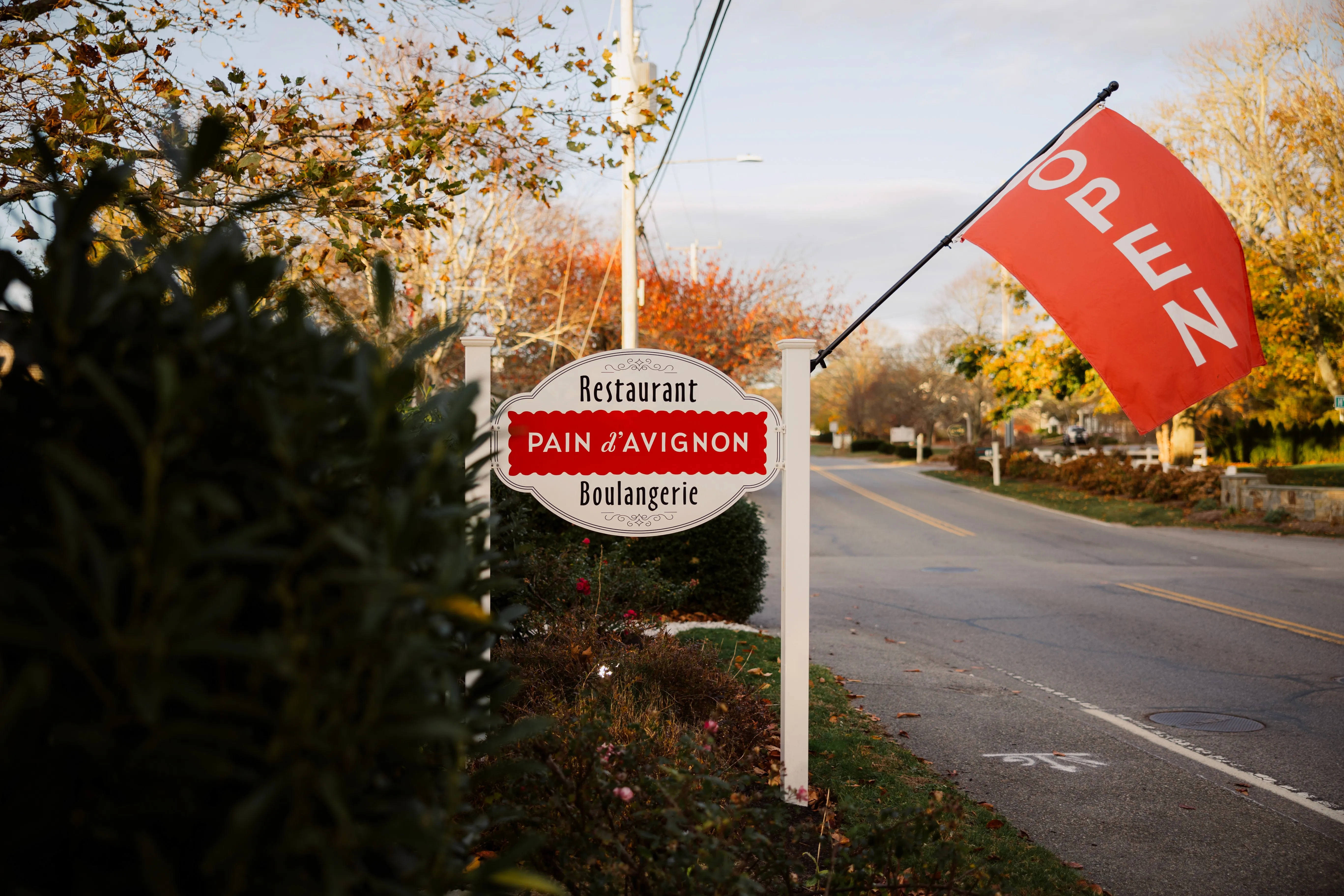 ain d'Avignon Chatham roadside sign — Restaurant · Boulangerie with red Open flag, Cape Cod
