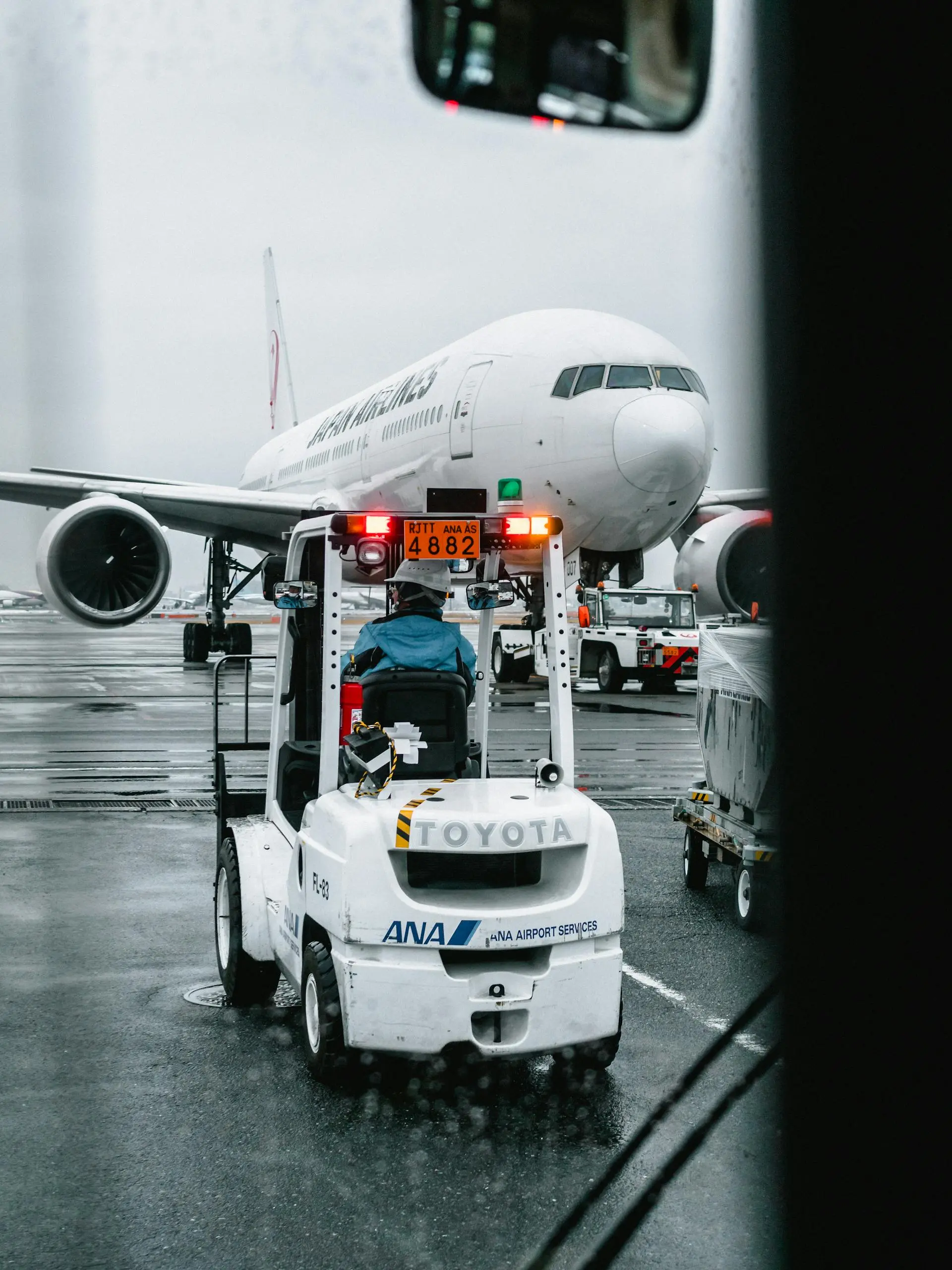 Airport ground crew loading cargo beside an aircraft on a rainy tarmac