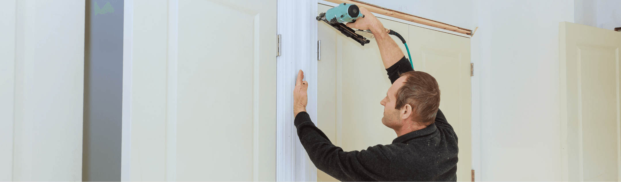 A man using a power tool to adjust or install a door frame in a bright indoor setting, focusing on precision as he works.