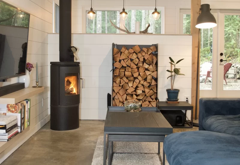 Modern two-story home with large glass windows, warmly lit interiors, and a balcony. Surrounded by trees and a manicured lawn at dusk. Cozy ambiance.