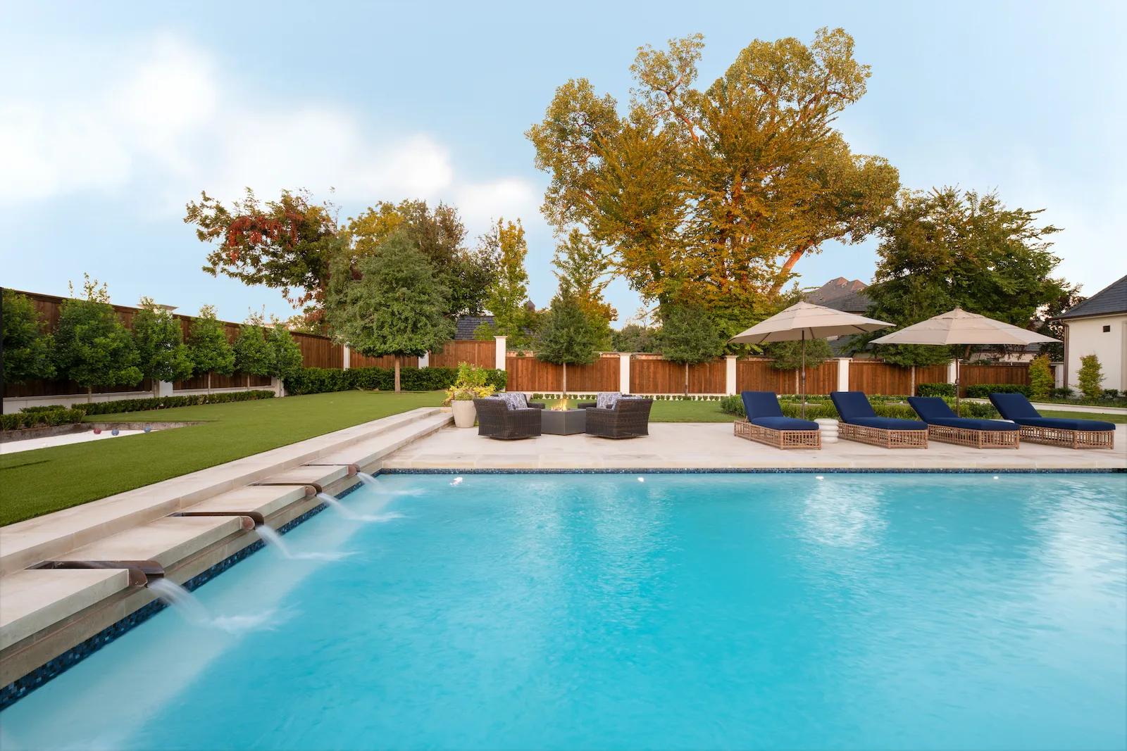 Custom pool water spout design with outdoor living area for luxury Dallas Fort Worth property by Blount Designs