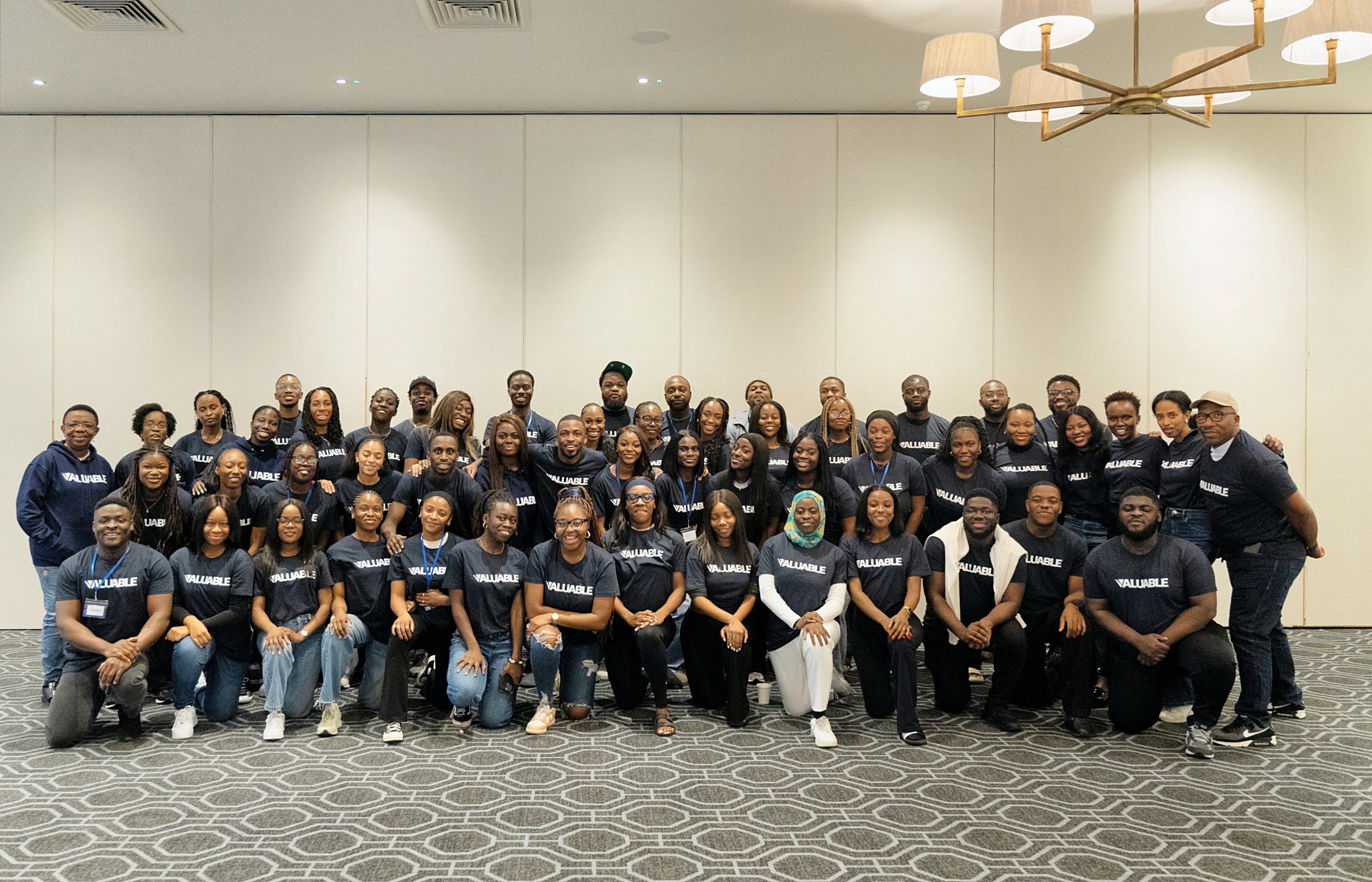 Large group of people from the Valuable community wearing navy sweatshirts, posing for a photo indoors.