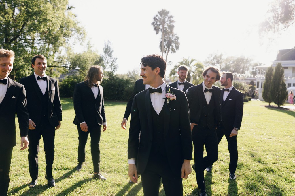     Wedding photographer in South Florida captures groomsmen walking together outdoors before the ceremony in golden light.