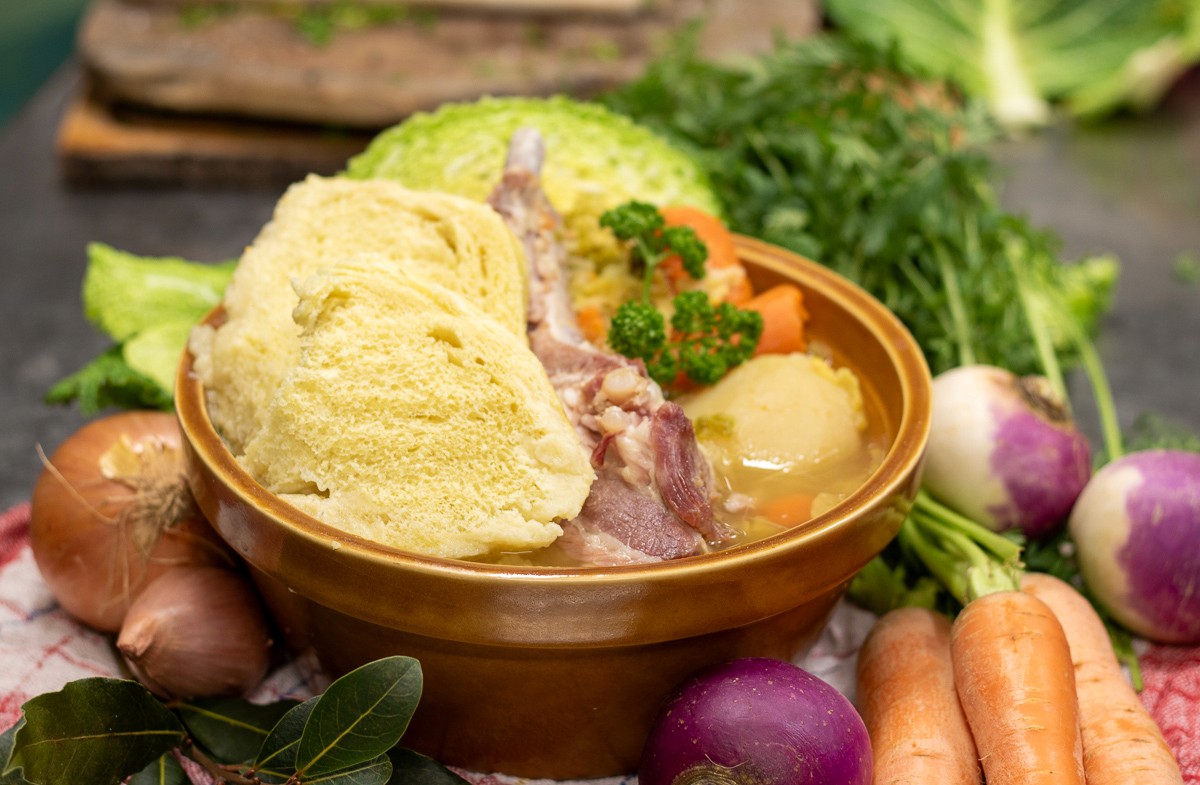 Freshly baked Margherita pizza with melted cheese, tomato sauce, and basil leaves, held by a person’s hand.