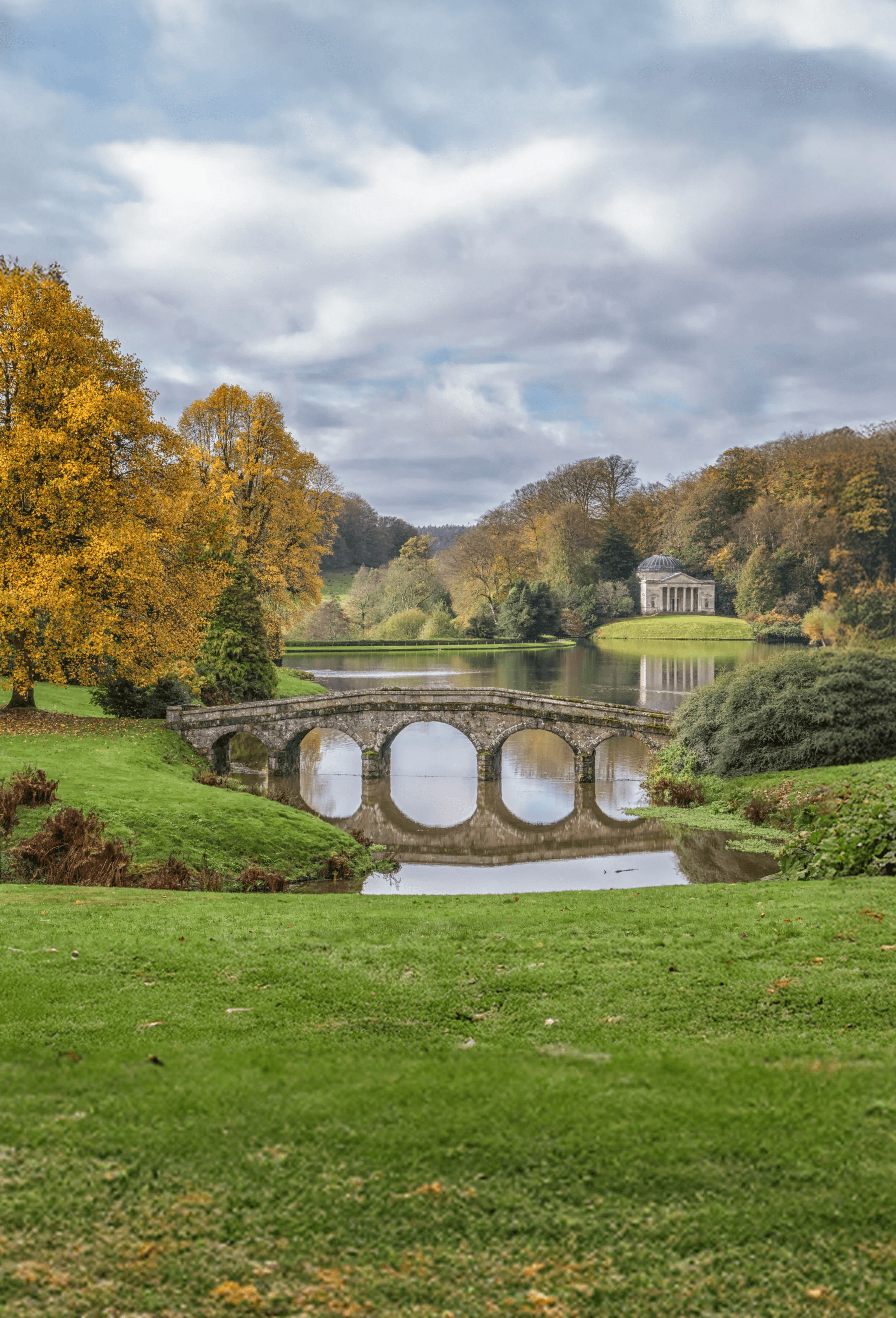 A stone bridge and classical temple at Stourhead Gardens, representing legacy, structure, and enduring continuity.