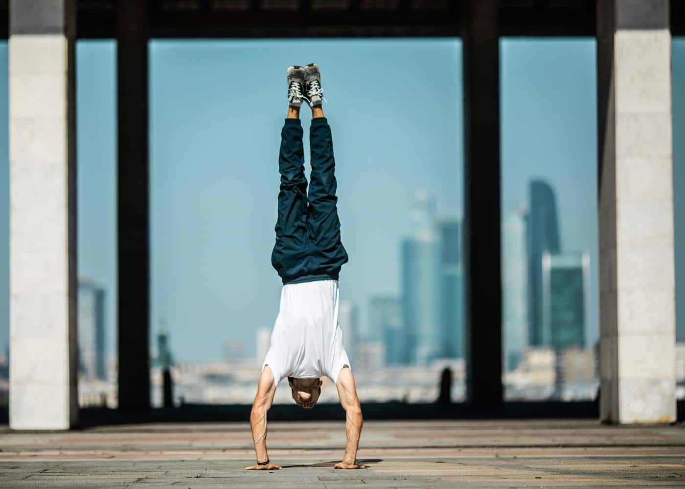 Man doing a handstand outside to showcase calisthenics exercises with buildings in the background