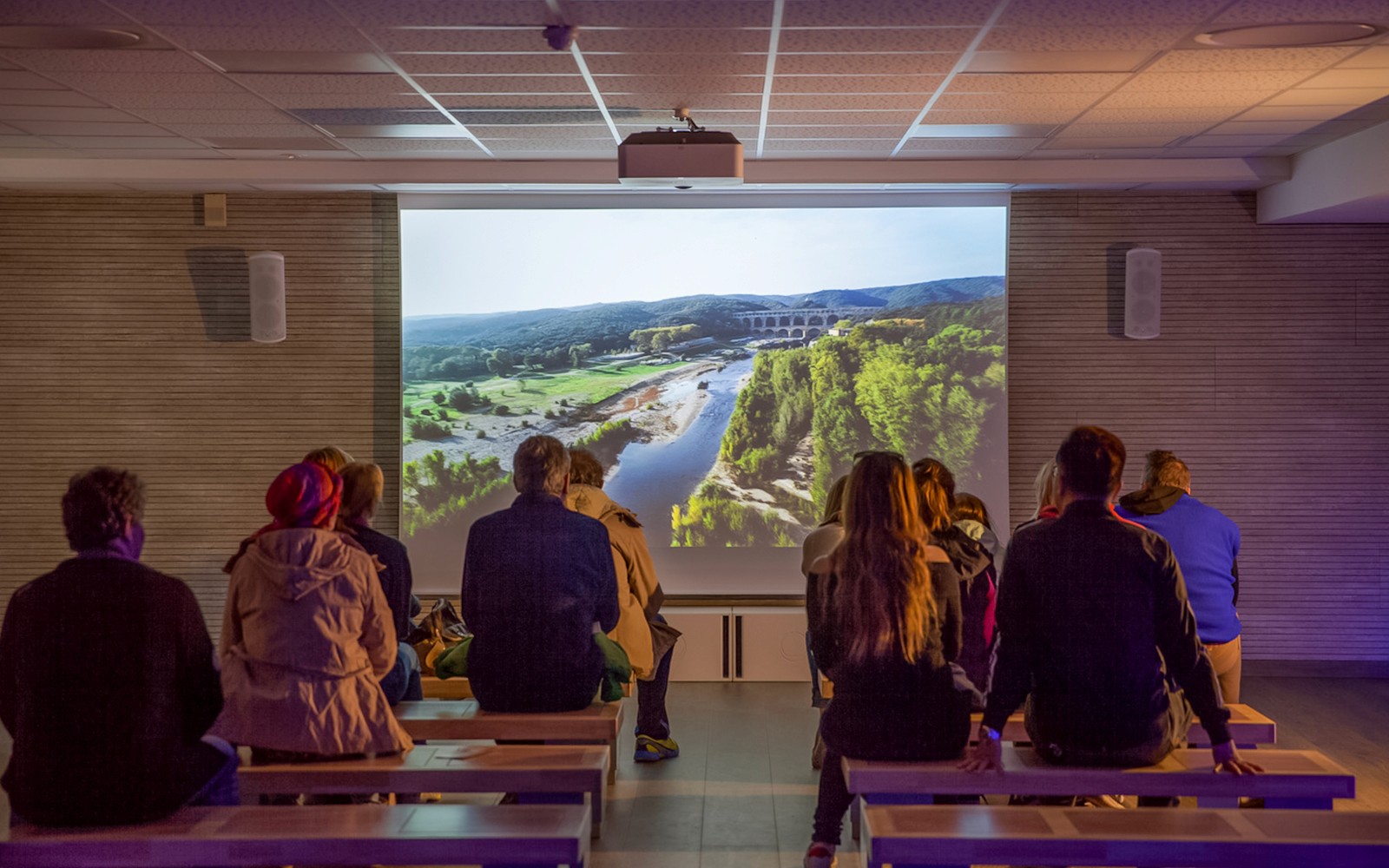 Visitors watching a Pont du Gard documentary in a museum cinema.