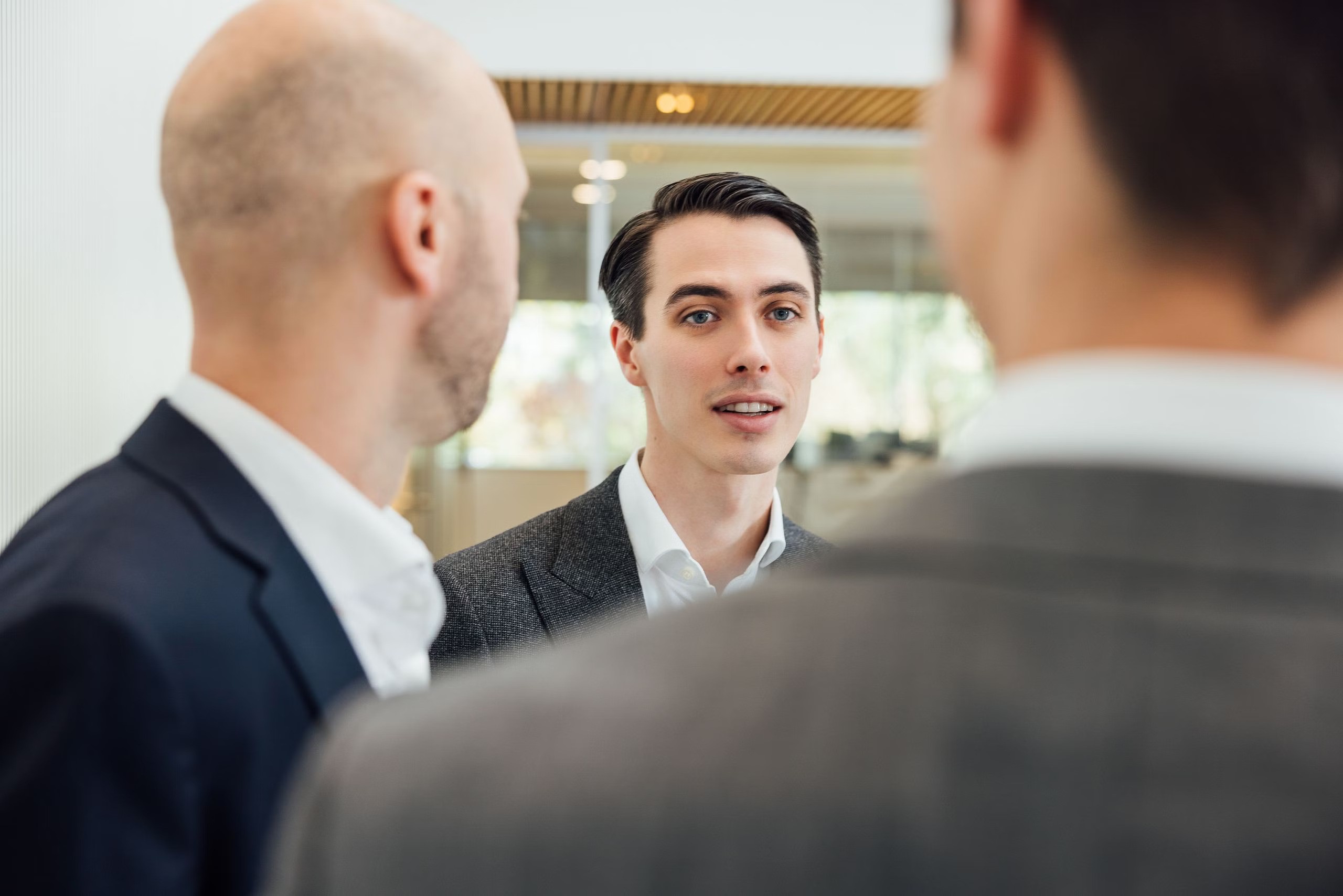 Three people in suits talking in a lobby