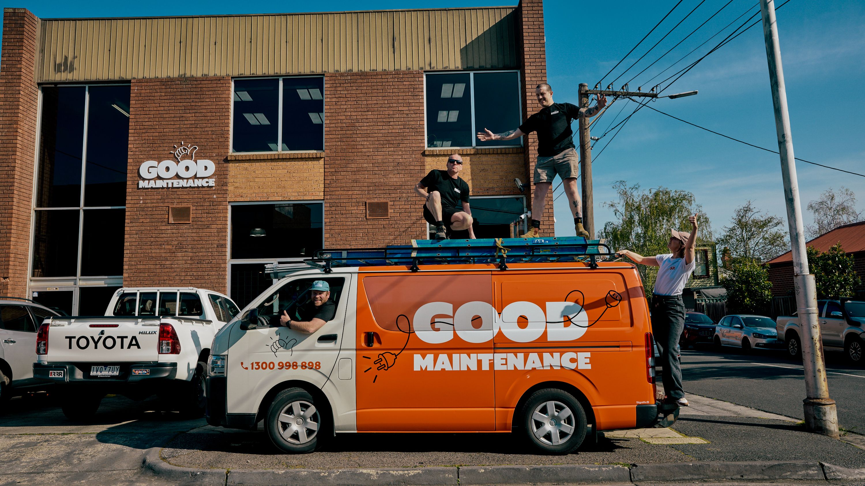Good Maintenance team members posing playfully on top of a company van