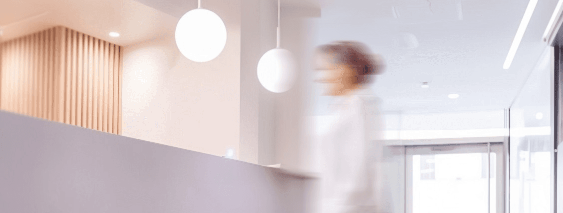 Blick aus der Froschperspektive in die Praxis auf eine Ärztin, die zum Tresen geht