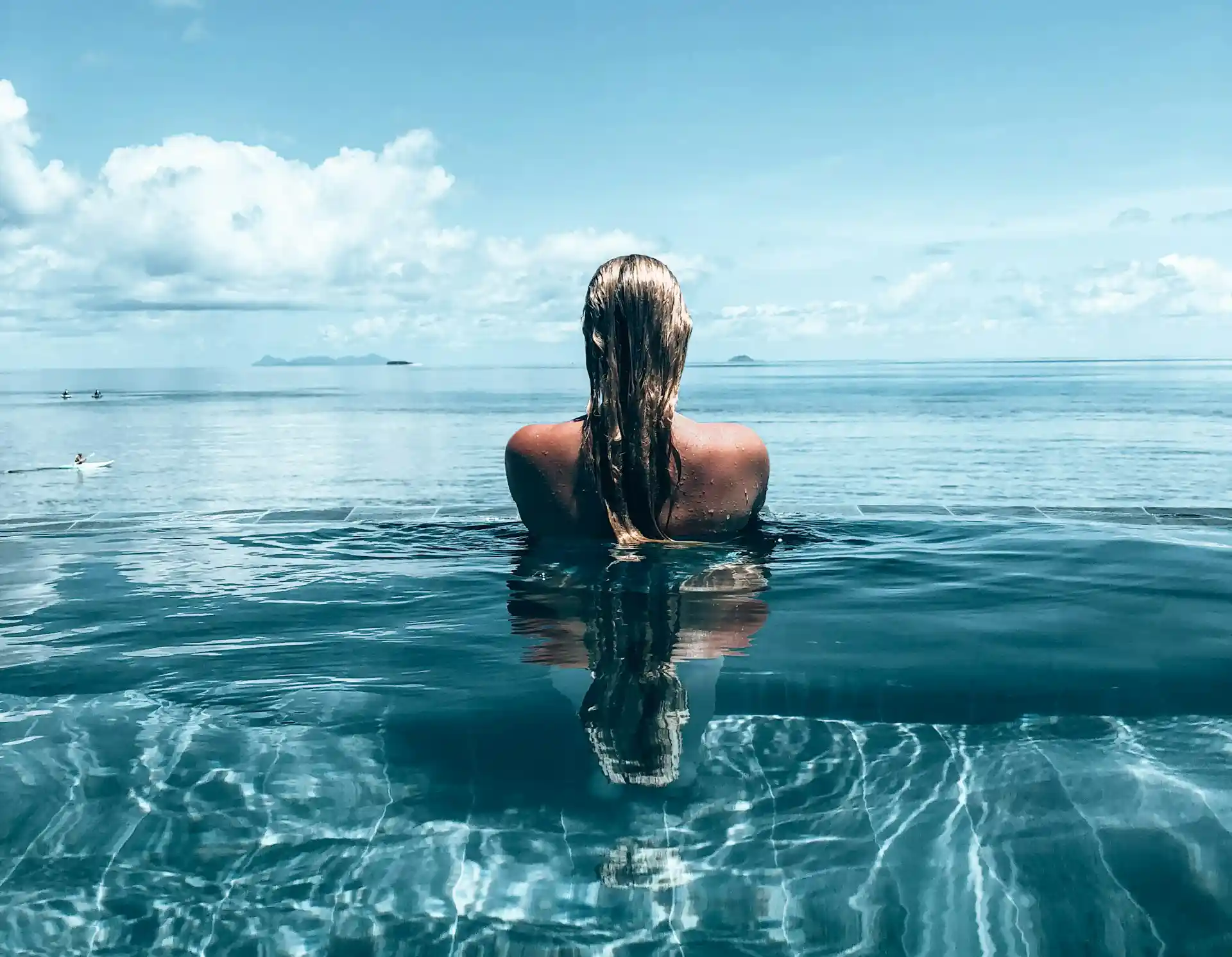 woman in an infinity pool overlooking the ocean