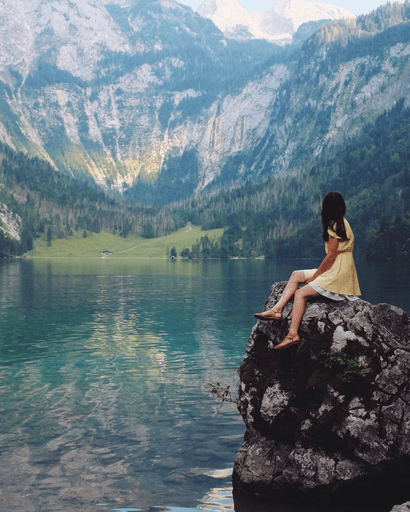 A woman sitting on a rock looking at the lake