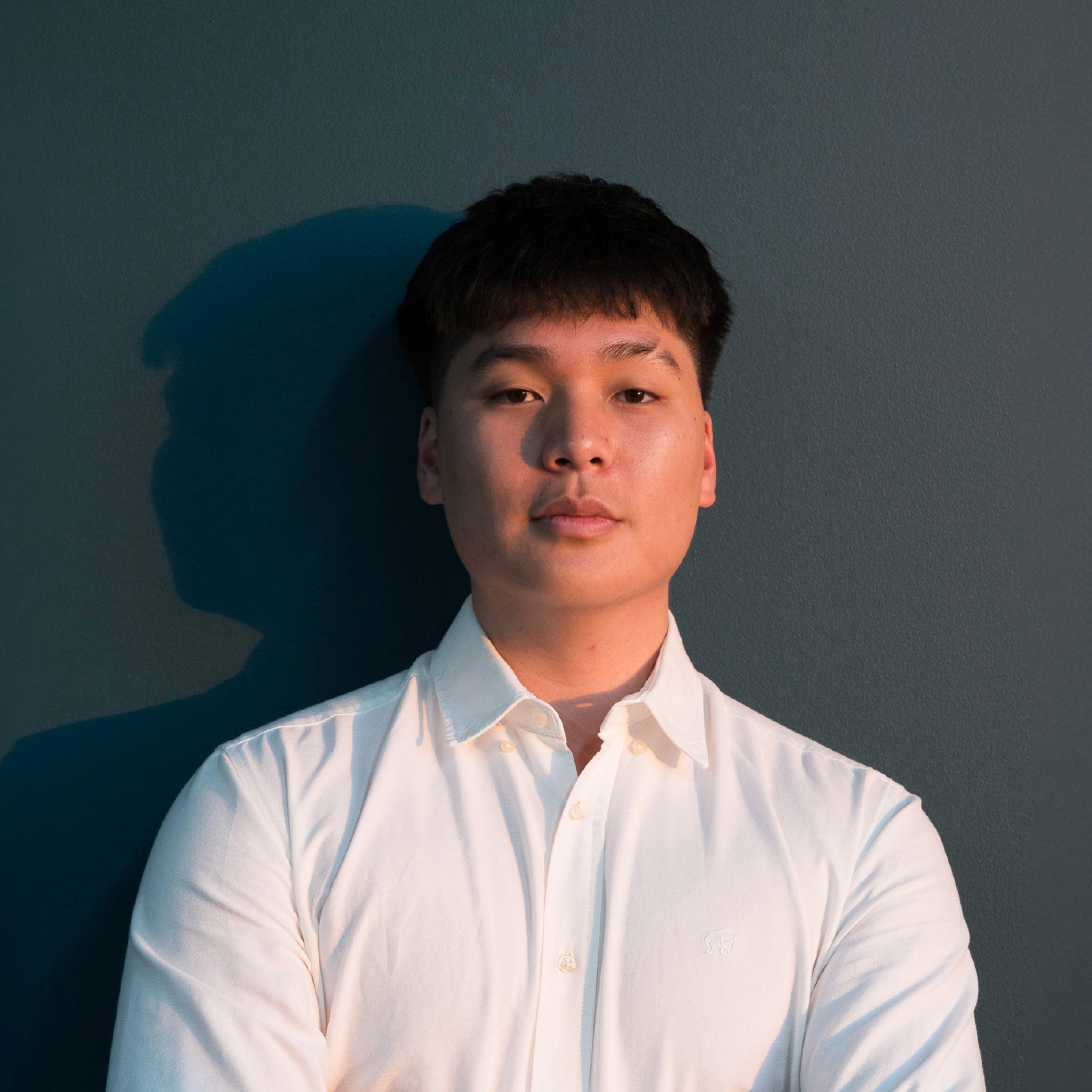 Portrait of Jack Le, Managing Director at Conxept Agency, in a white shirt, standing against a dark background with soft lighting and a confident posture.