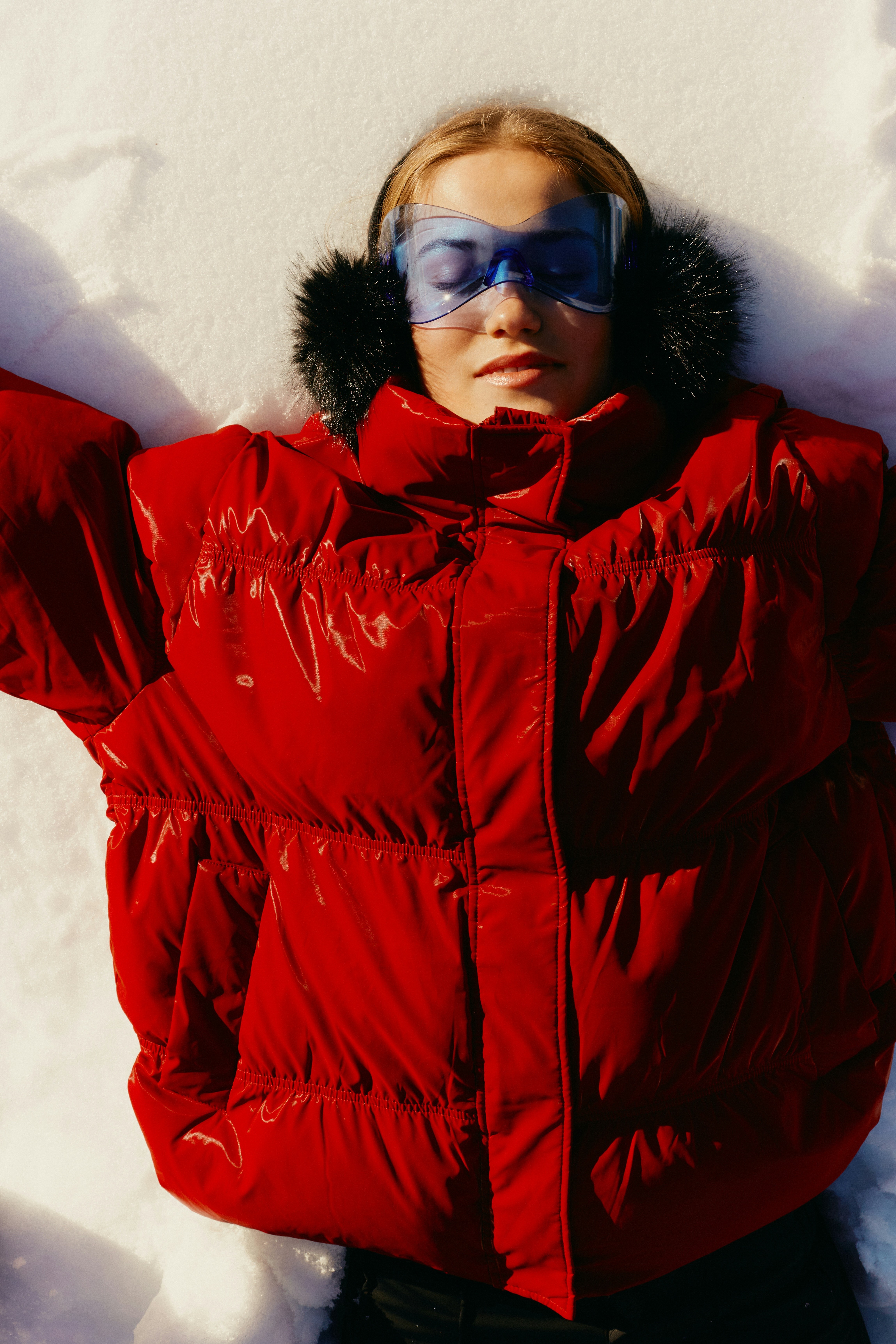 women lying in snow with red puffer jacket