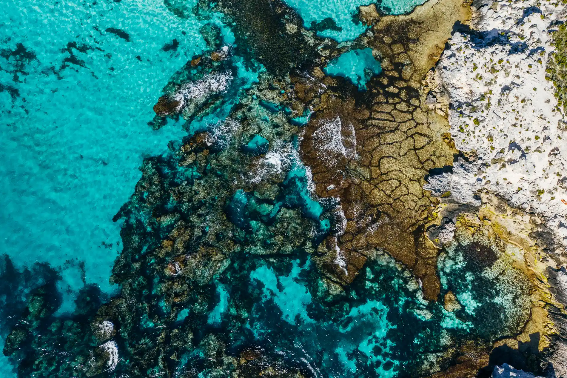 Aerial looking down on reef ledges and channels in clear turquoise water