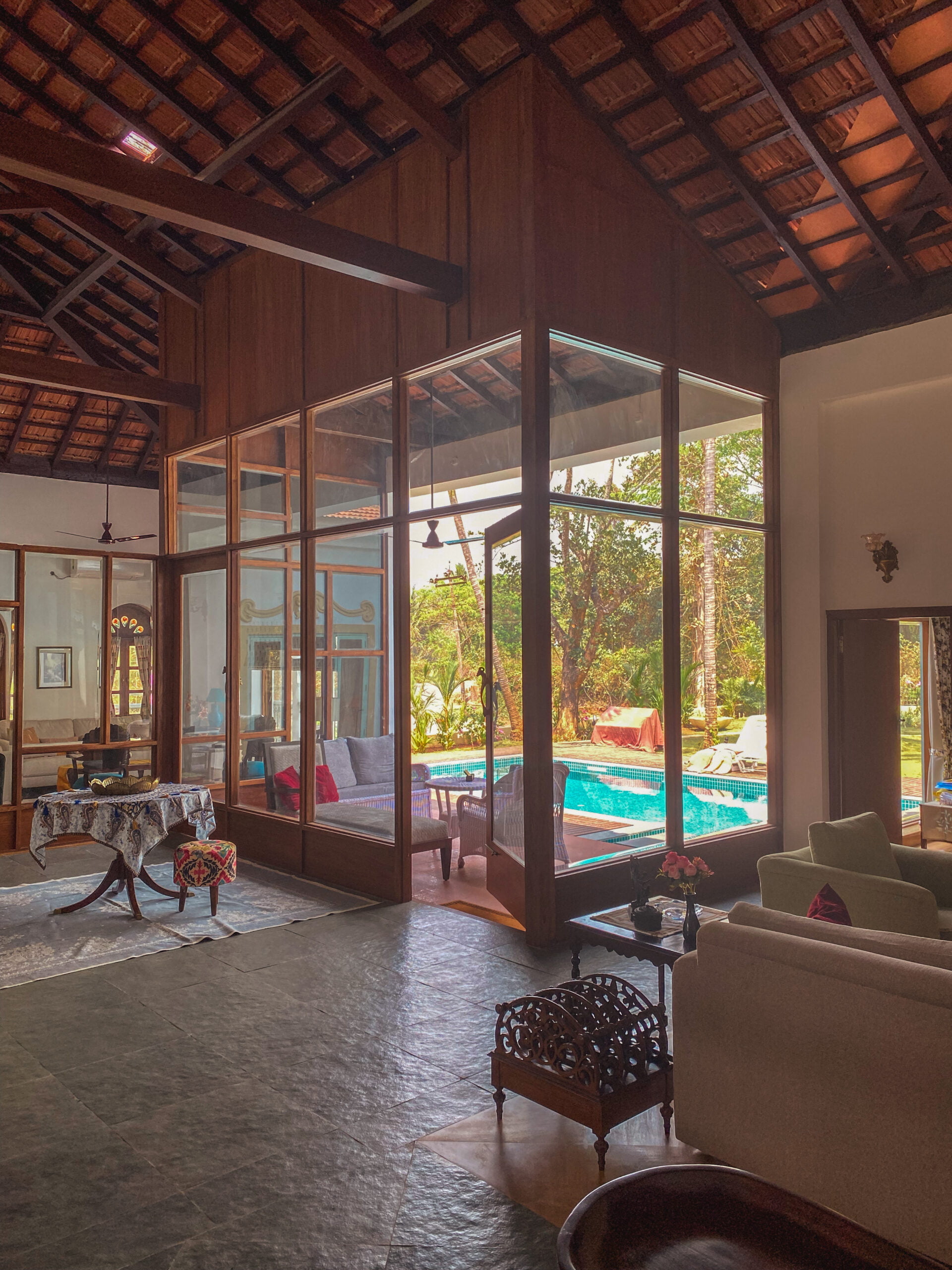 The grandeur of the high, exposed-truss ceiling is balanced by the serenity of the garden view, framed perfectly by the large glass structure