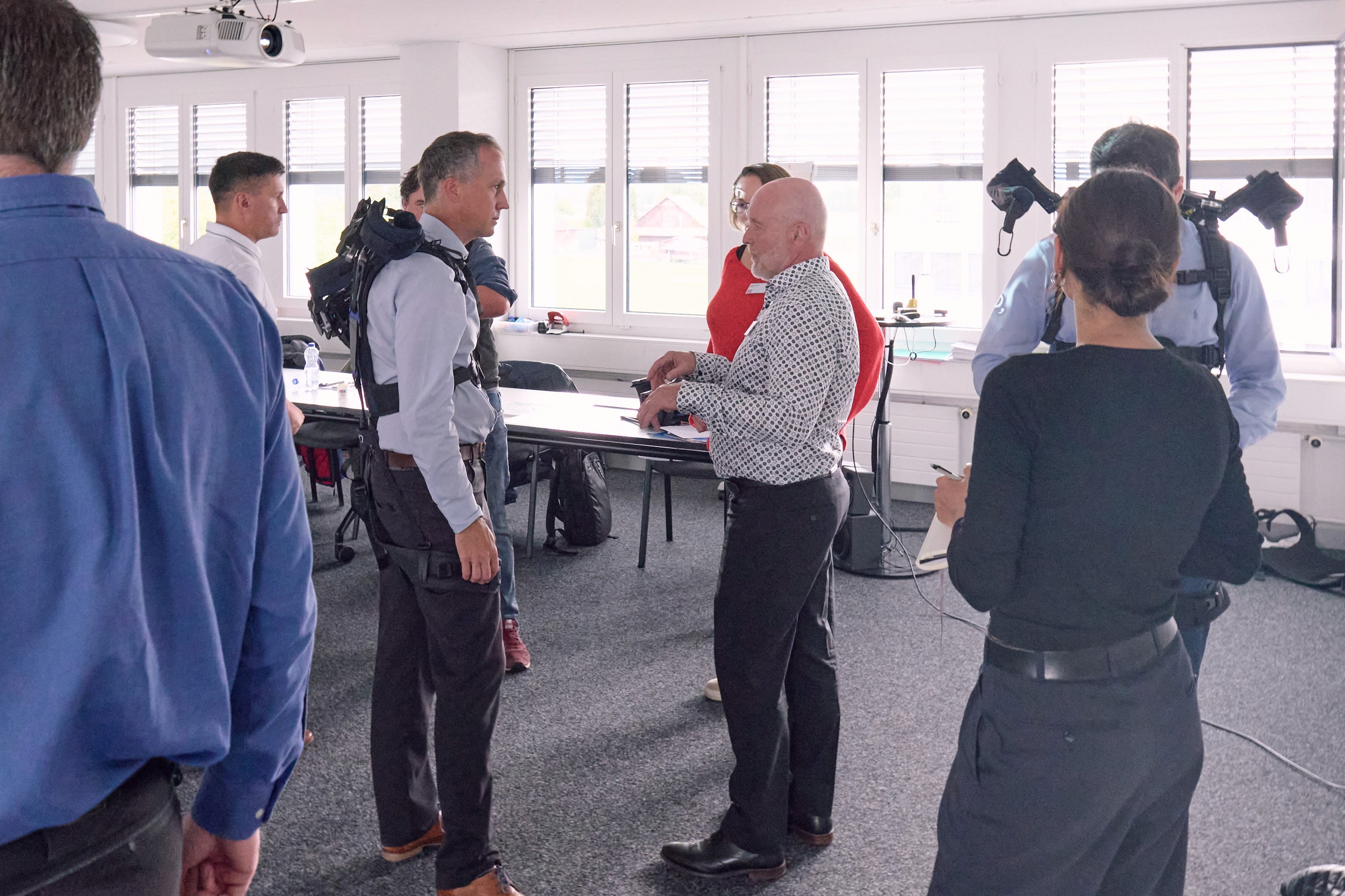 Workers in ergonomic training wearing exoskeletons in the workplace, demonstrating and supporting occupational health and safety to reduce musculoskeletal disorders.