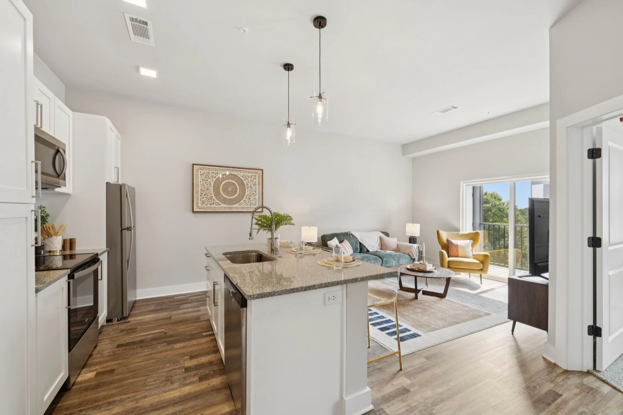 Open concept kitchen and living room featuring modern decor and ample natural light, creating a spacious and inviting atmosphere.