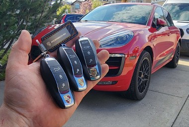 carkeyaction technician holding duplicated porsche keys in front of the vehicle