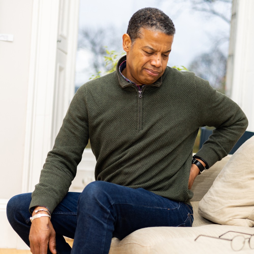 Man sitting down, holding his lower back