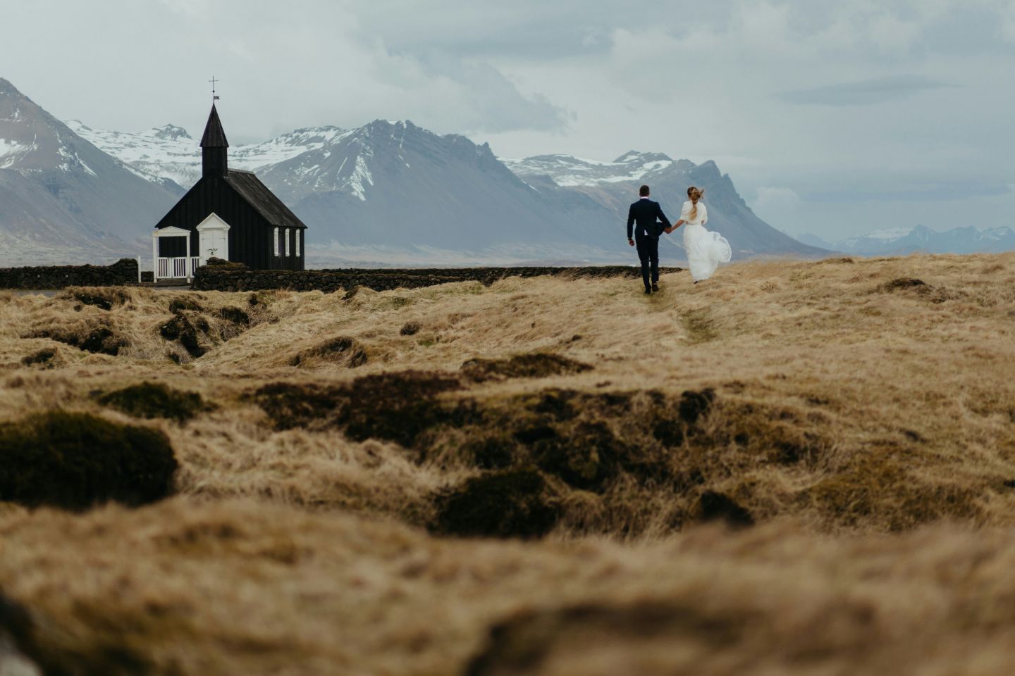 Wedding couple walking toward Búðir Black Church in Iceland.