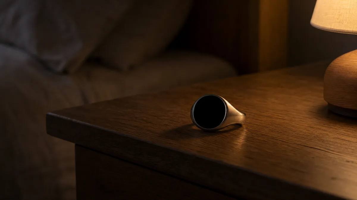 Smart tasbih ring on a wooden nightstand with its face dark in low warm night light