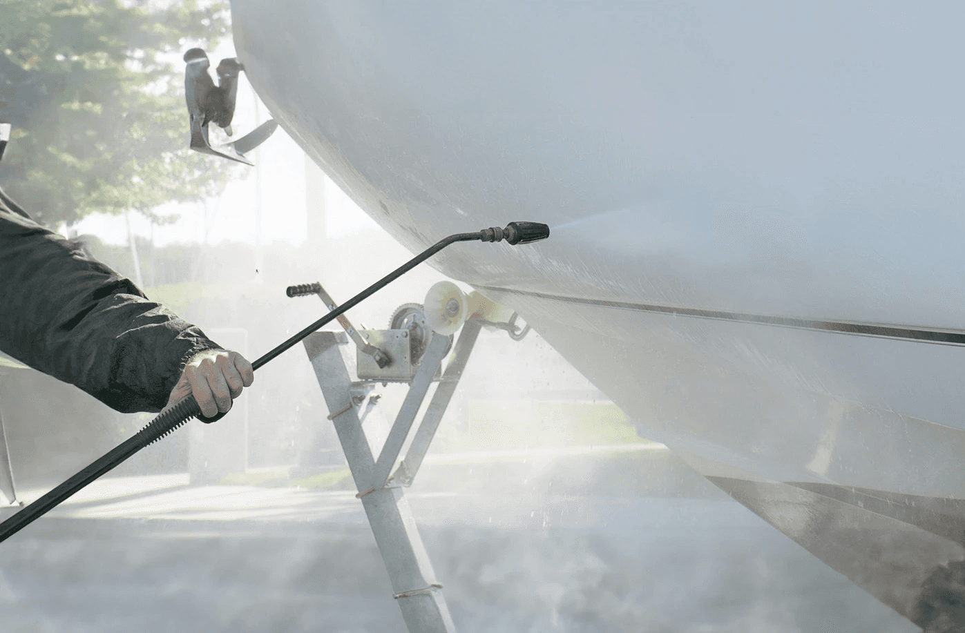 A boat being sprayed by acid and water, the hull is being cleaned with acid wash
