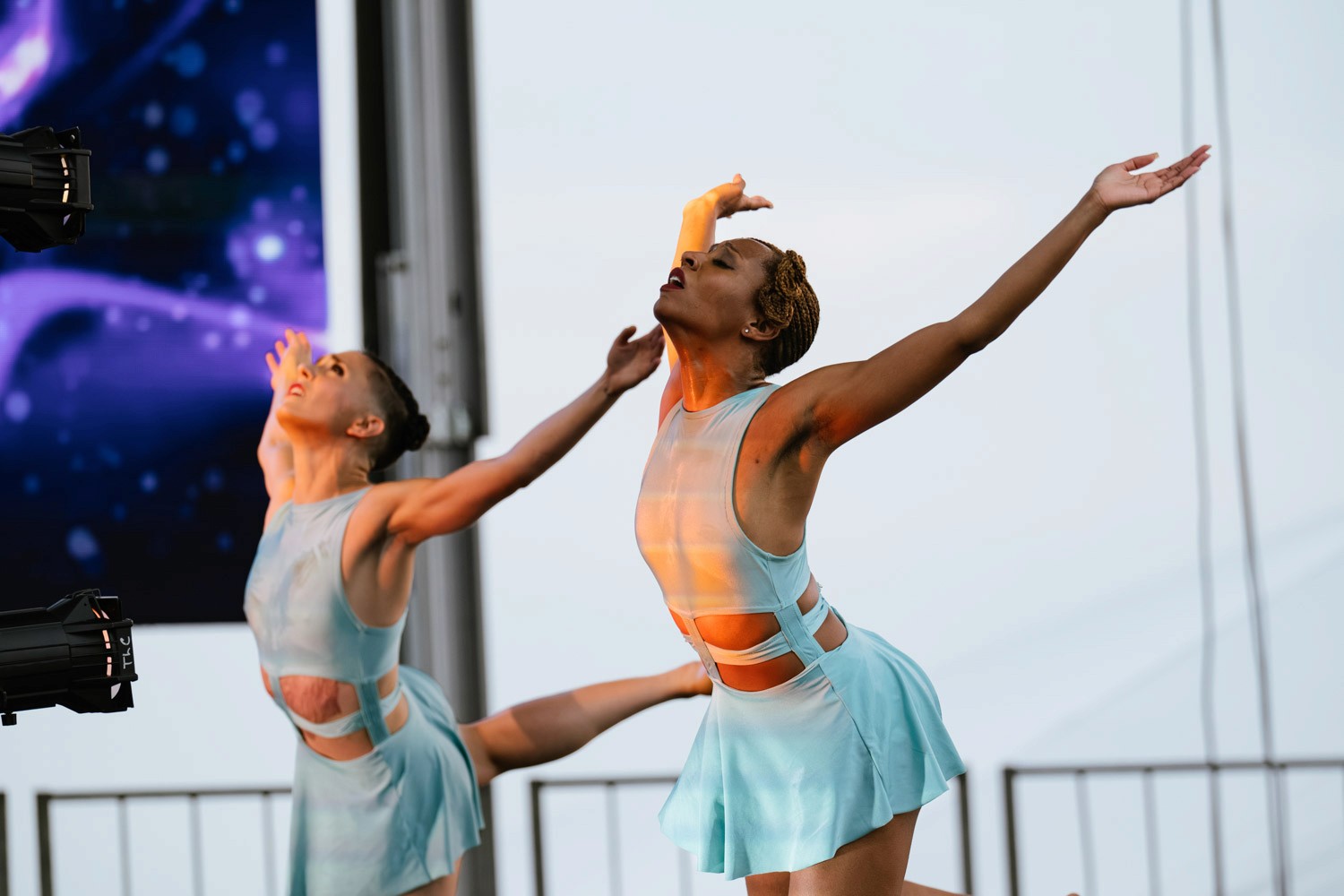 Two dancers perform together in pale costumes.