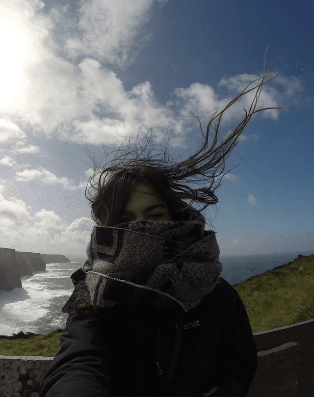 Jane bundled up on the Cliff's of Moher, hair blowing in the wind
