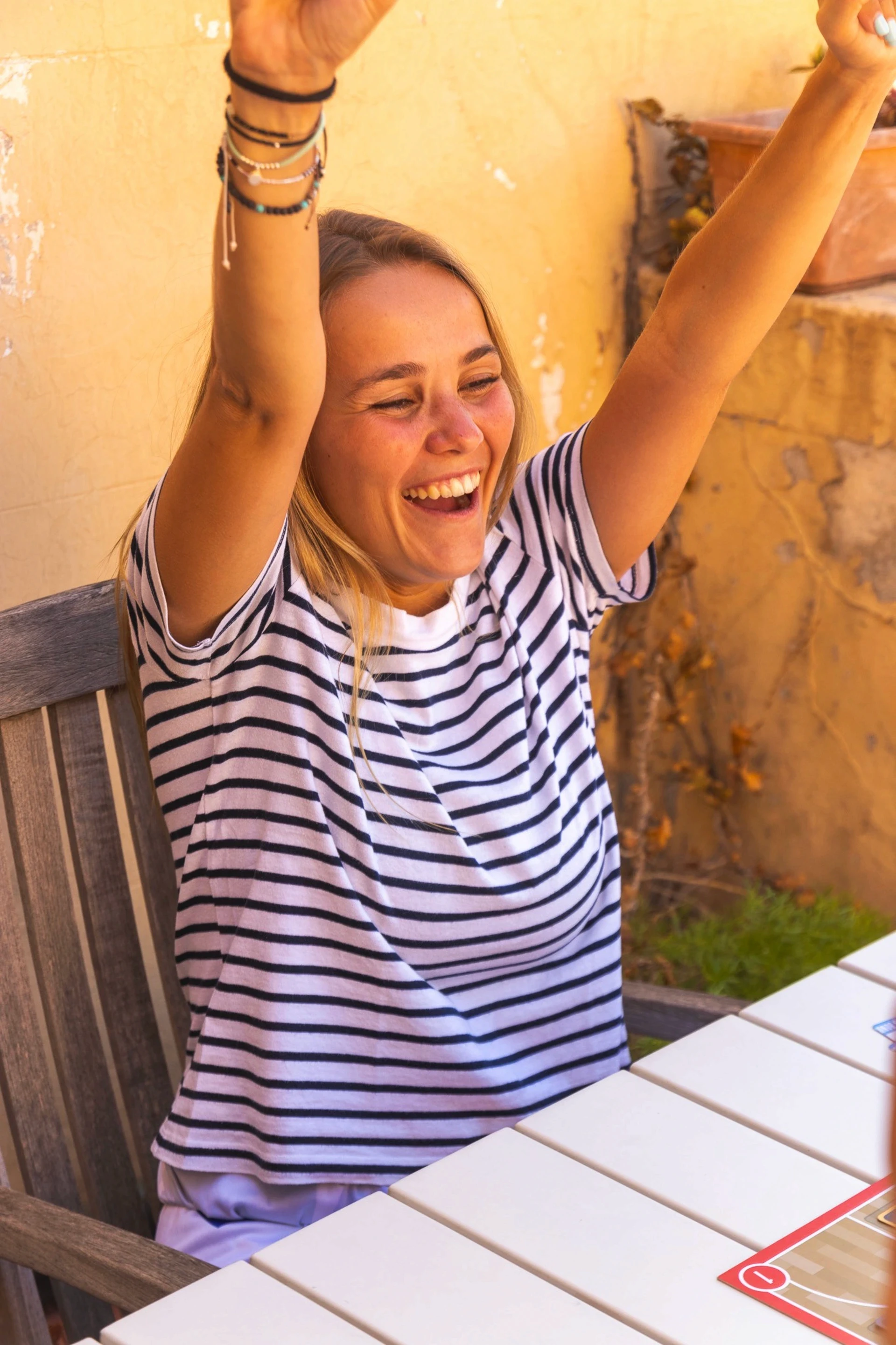 Young woman with arms raised, laughing joyfully.