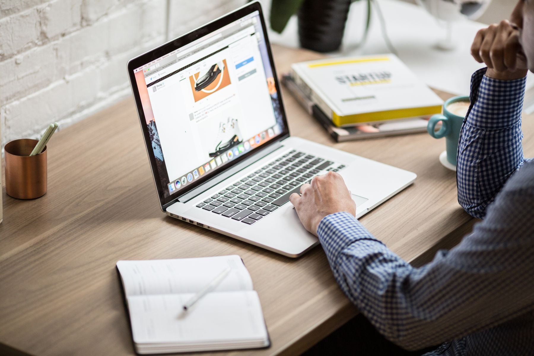A man researching products online using a laptop and notebook