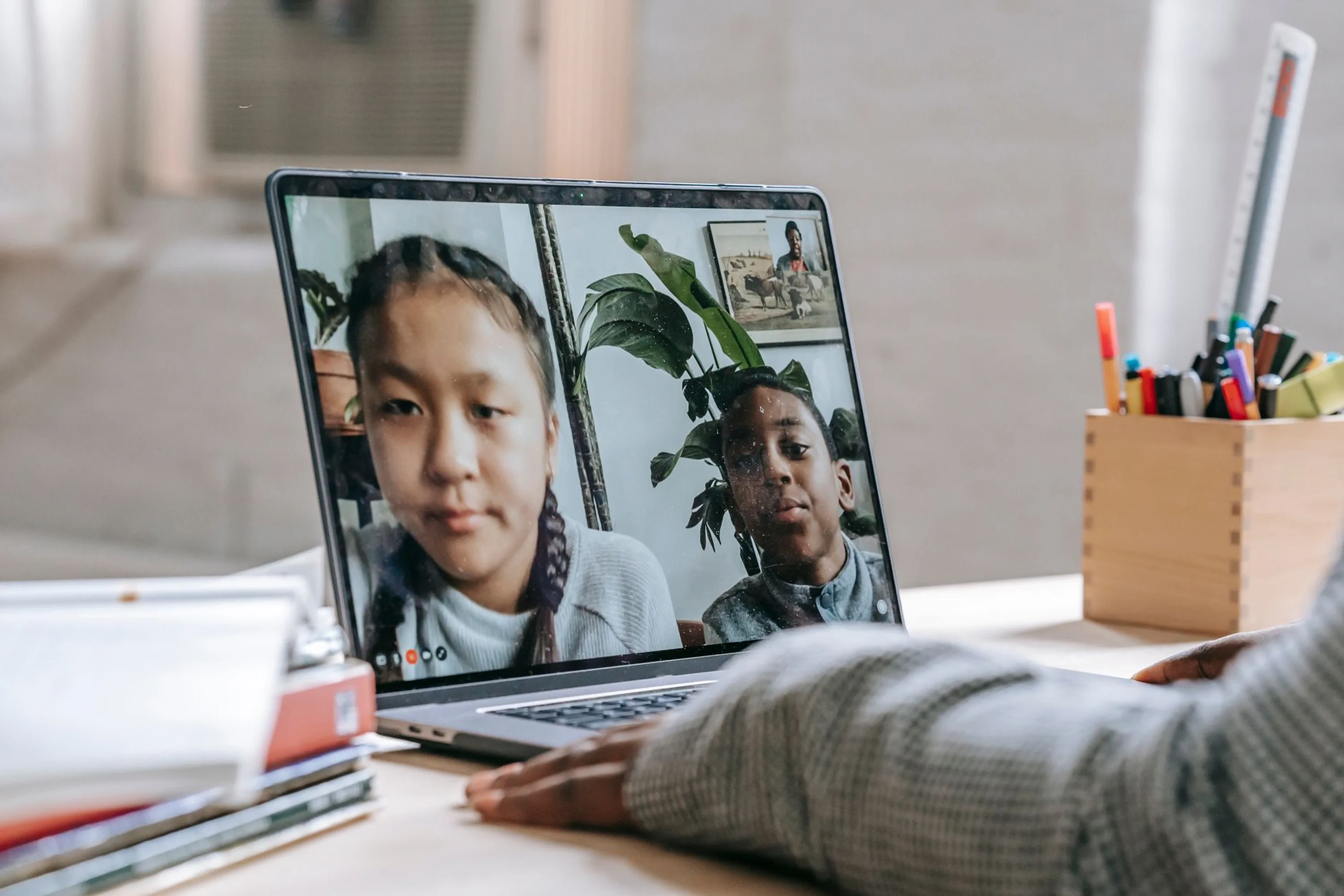 A close-up view of a laptop monitor during a remote video conference, capturing the interaction between students and an instructor during a virtual classroom meeting.