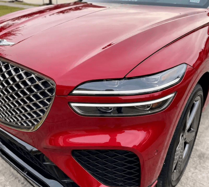 Mobile headlight restoration service in Houston featuring a red Genesis GV70 with clear, polished headlight lenses.