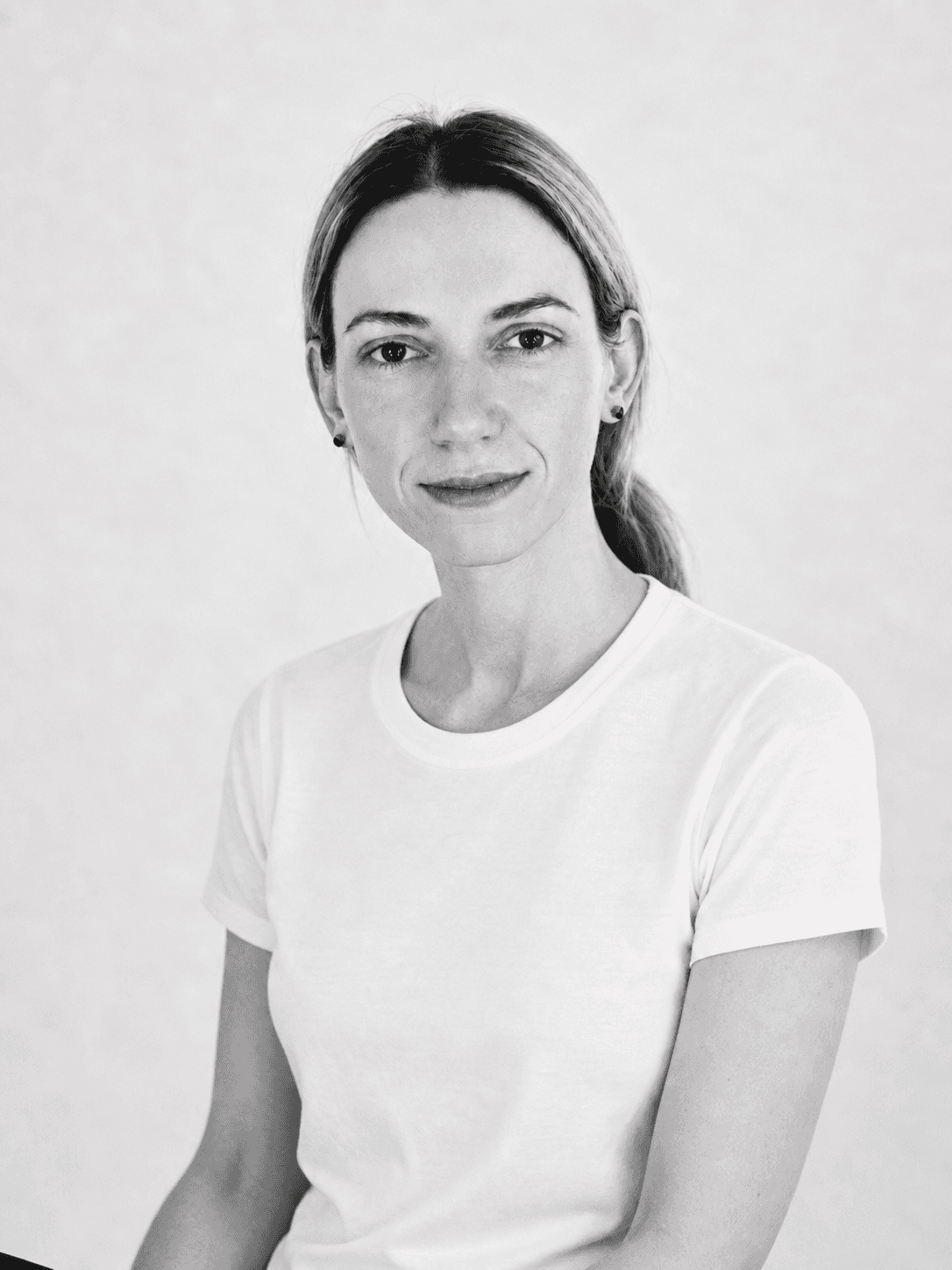 Black and white professional portrait of a female designer in a white t-shirt against a light studio background