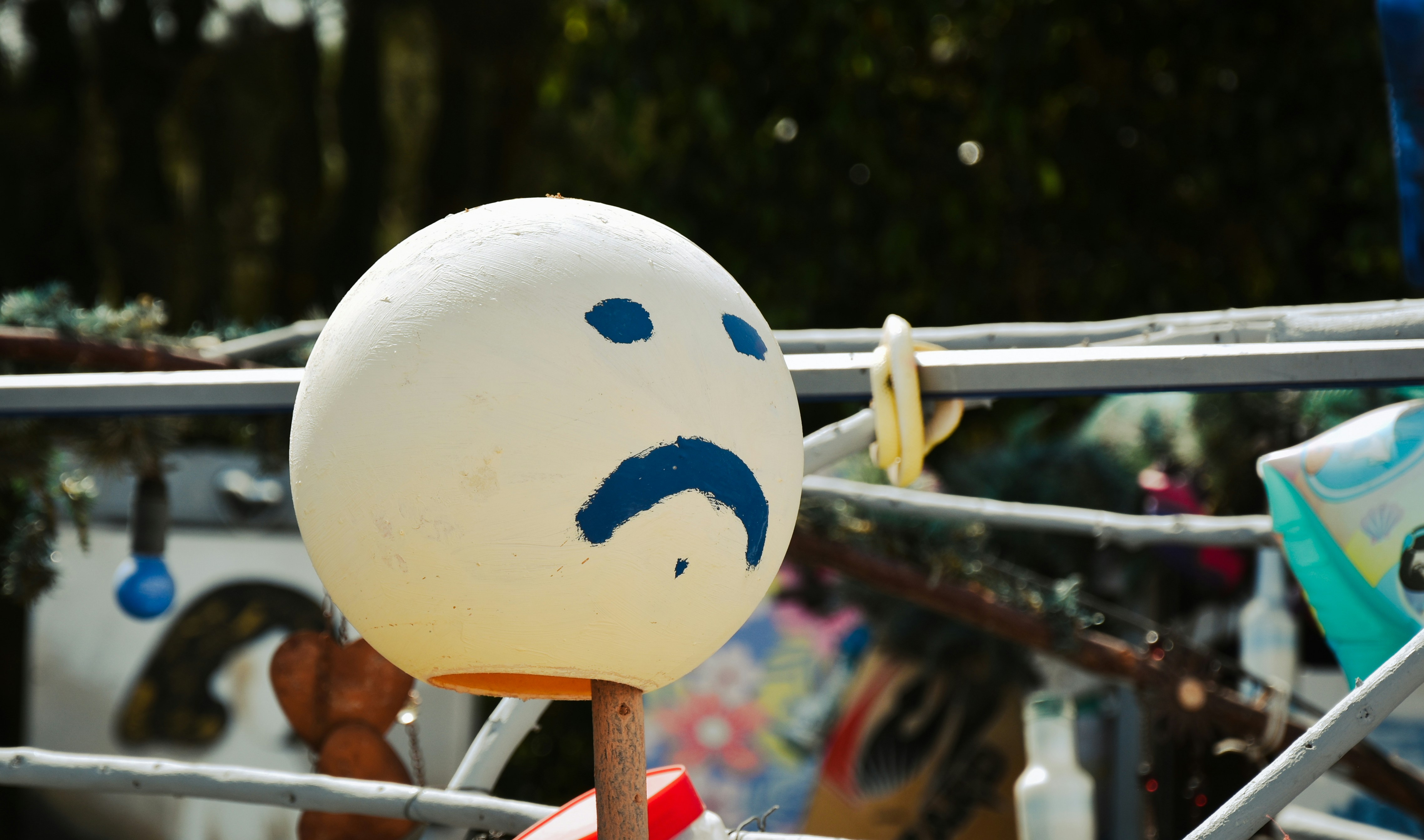 A white sphere with a sad face painted on it.