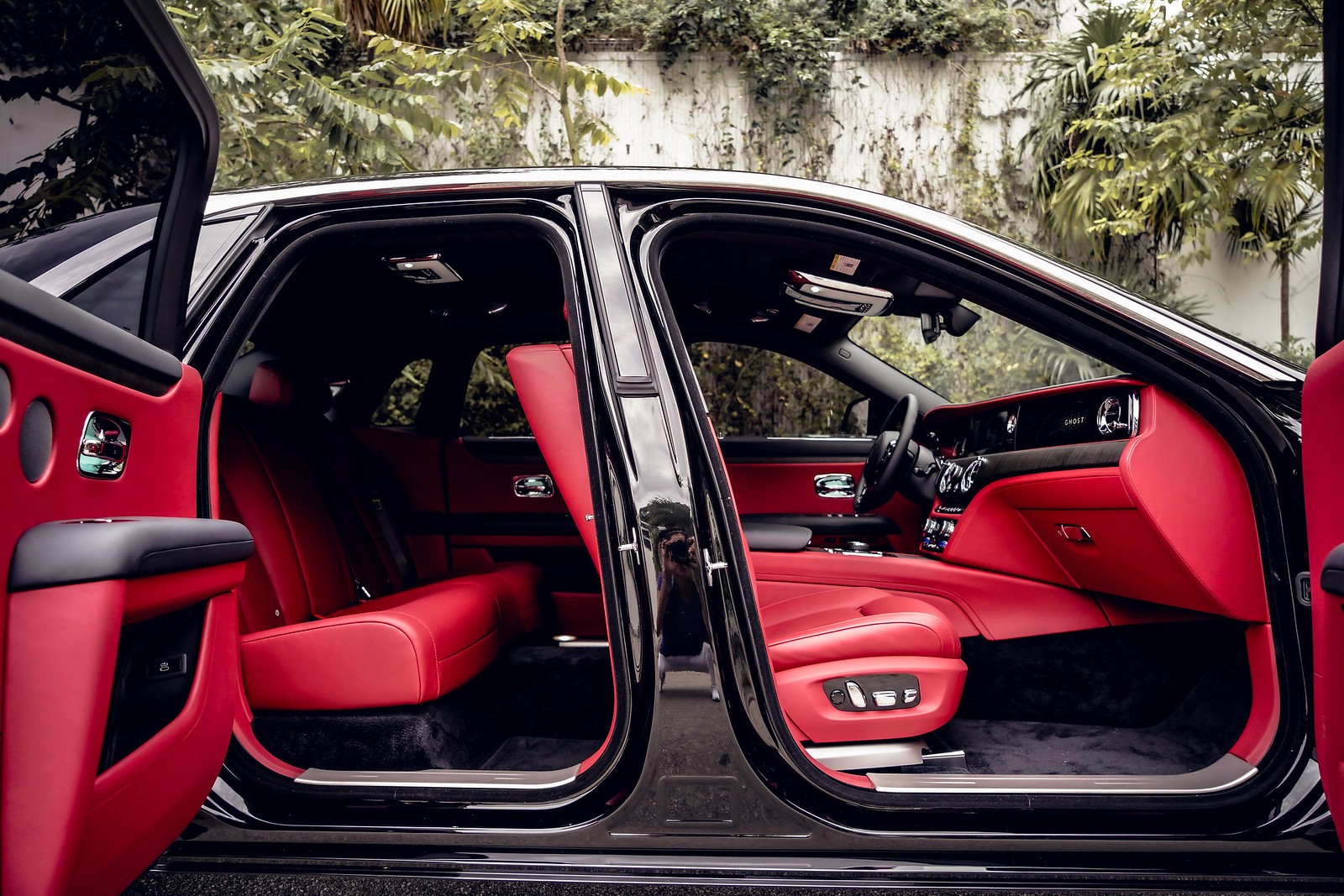 Side shot showing the interior of the Ghost with the doors open, emphasizing the luxurious red leather seats and rear-hinged doors.