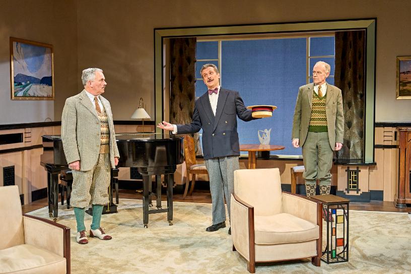 Three men in vintage suits sharing a comic moment in a living room scene from Fallen Angels.