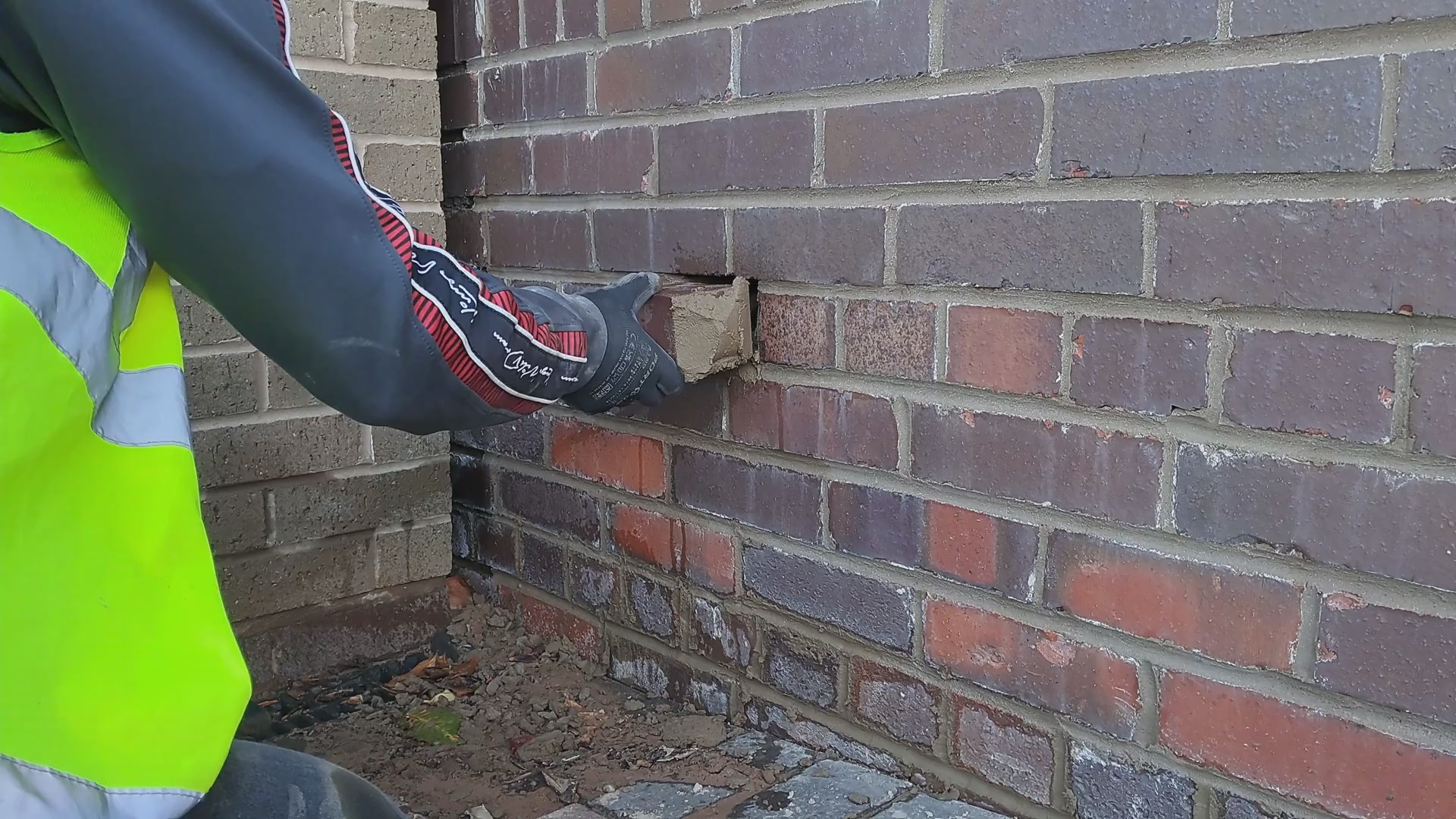 A man replacing abrick on a garden wall