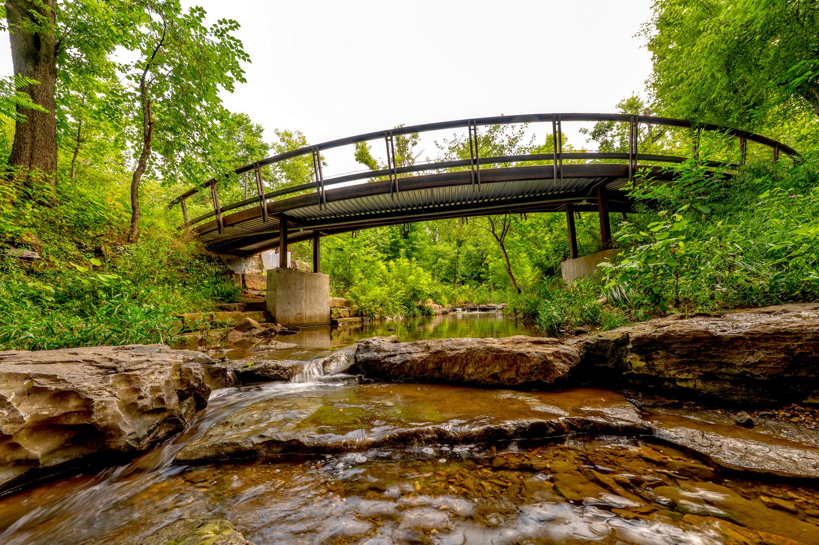 Clear creekwater flows under a curving bridge