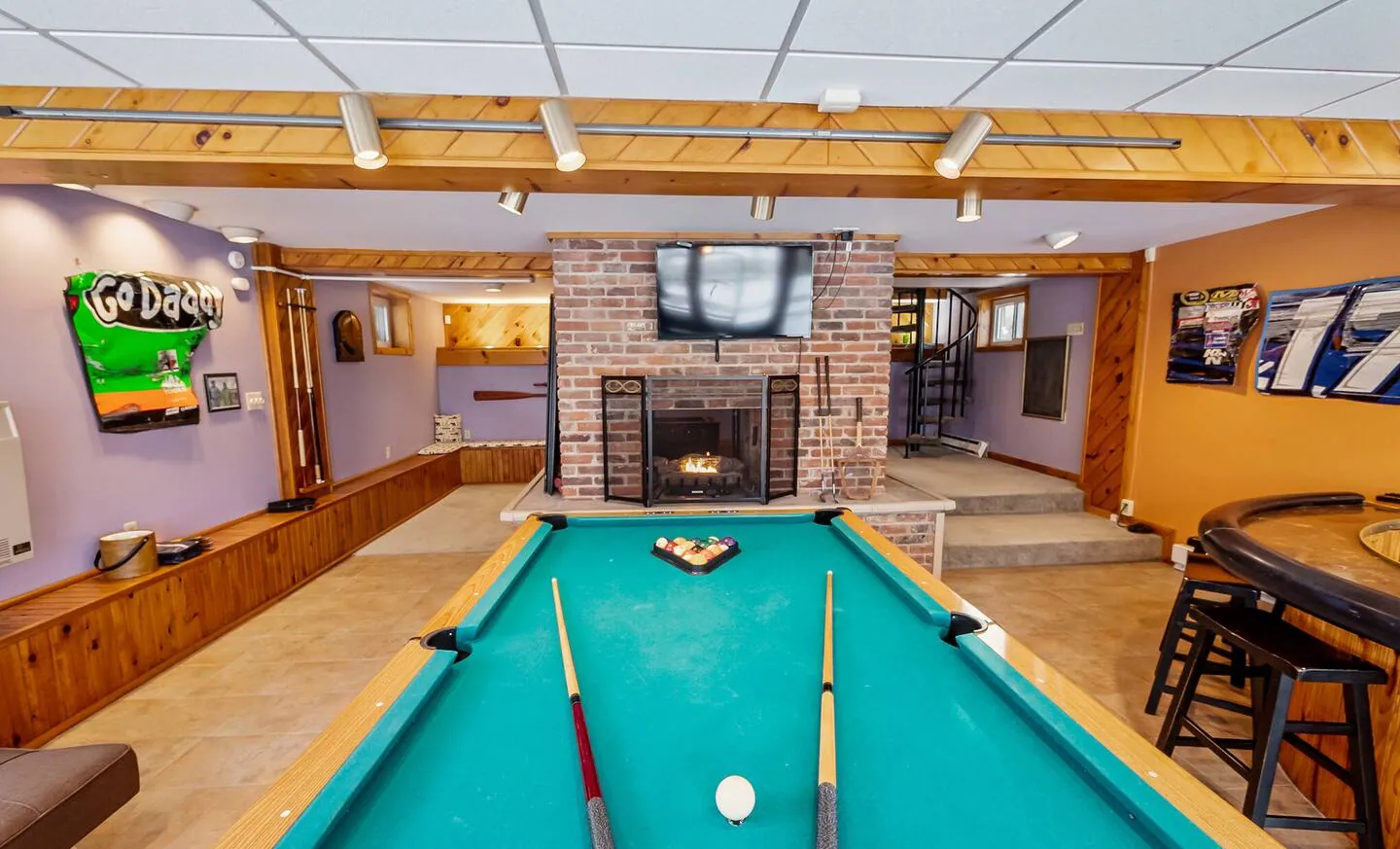 Pool table with racing decor and brick fireplace in the game room at Repeat Retreat