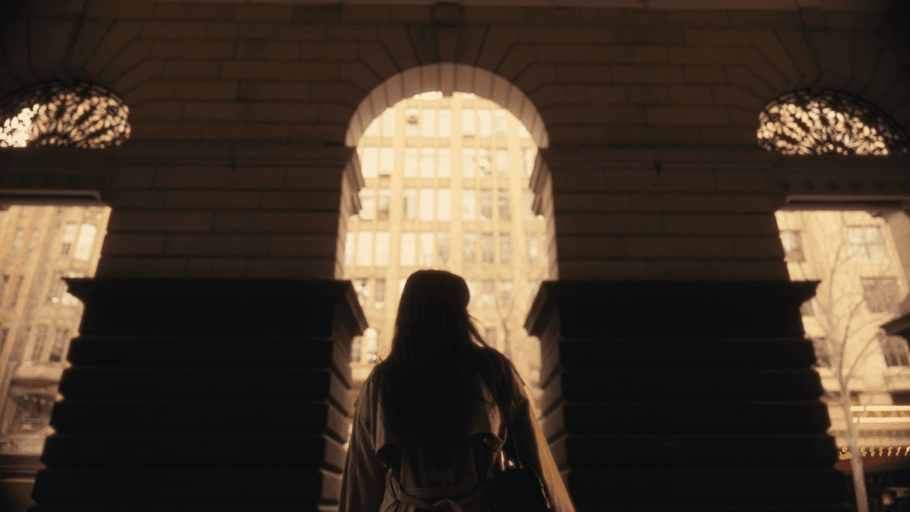 A woman standing in front of a large, illuminated archway in a dimly lit interior space