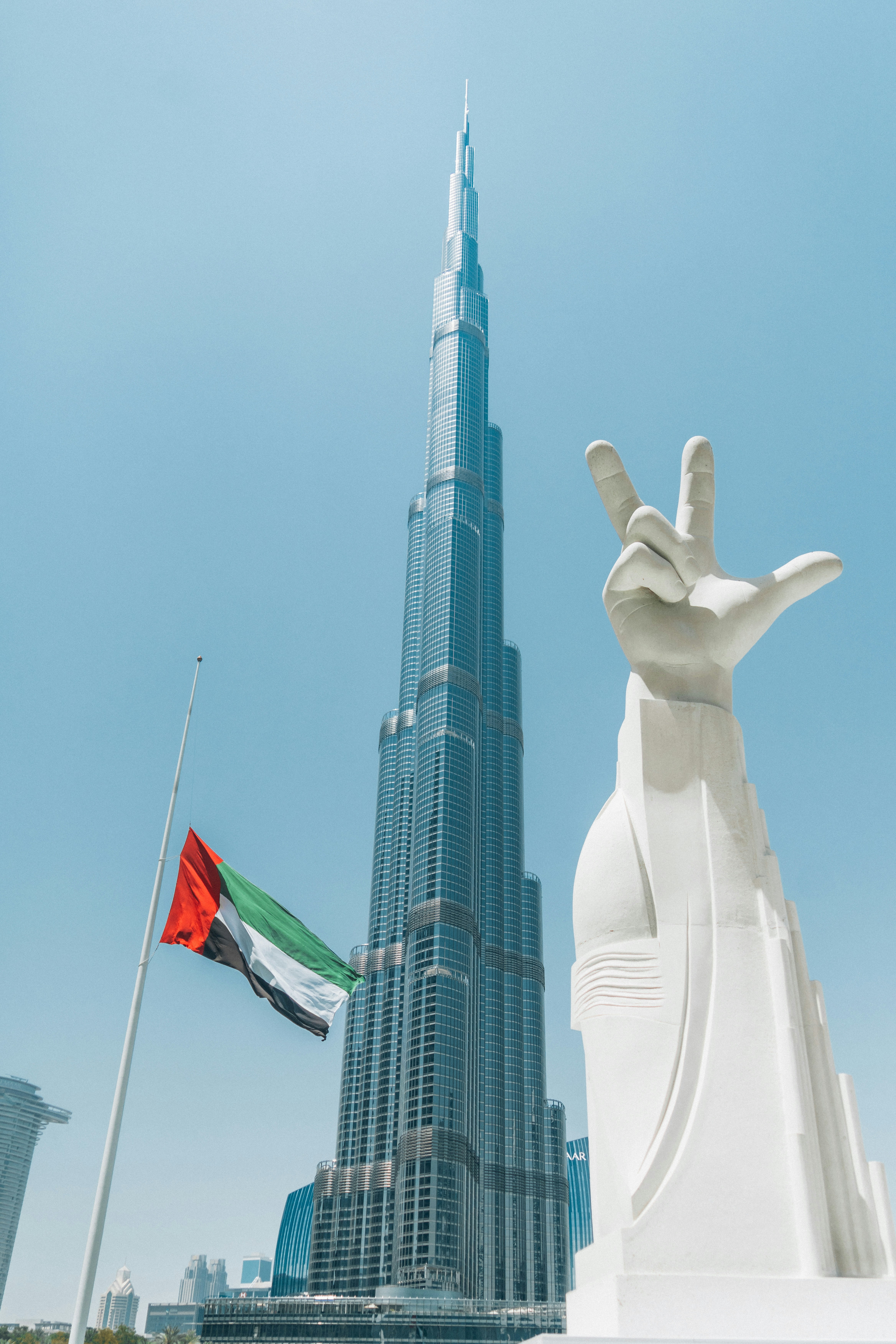 a statue of a hand and a flag in front of a tall building