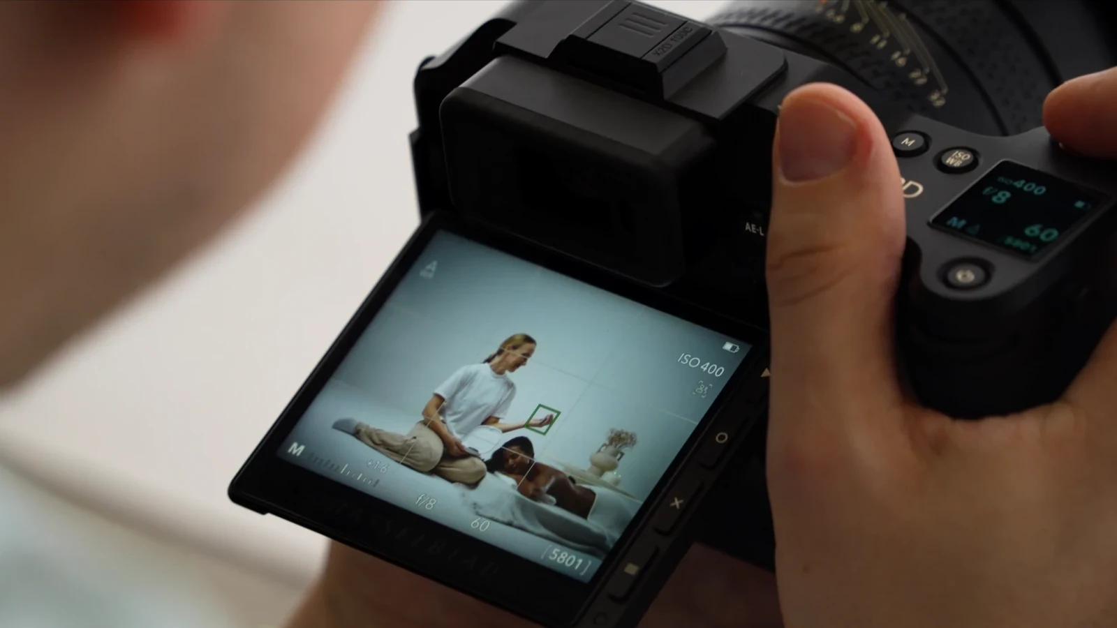 Behind-the-scenes photographer framing the massage scene on a Hasselblad