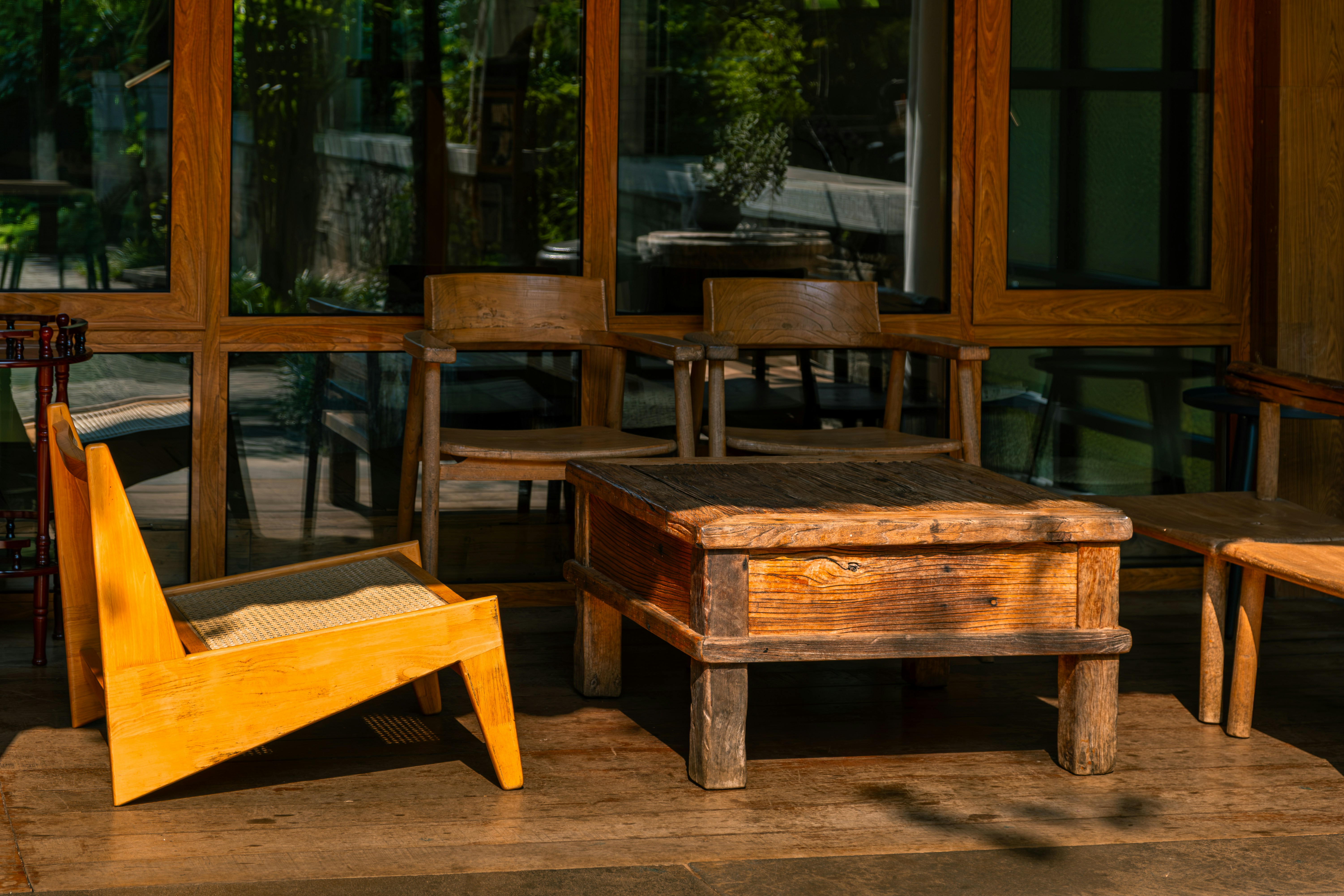 Wooden furniture sits on a sunny porch.