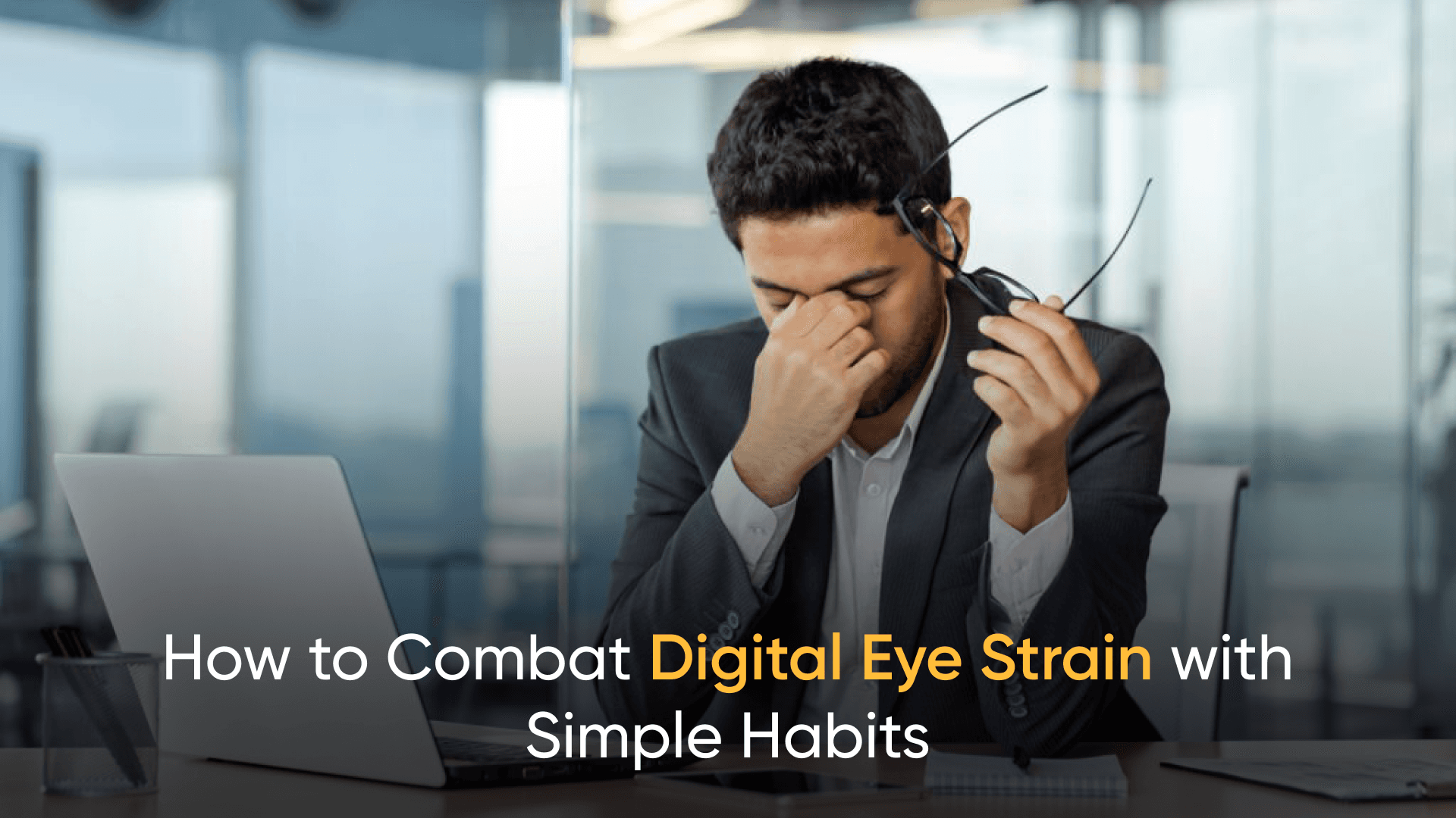 A stressed professional experiencing digital eye strain, removing glasses while sitting in front of a laptop.