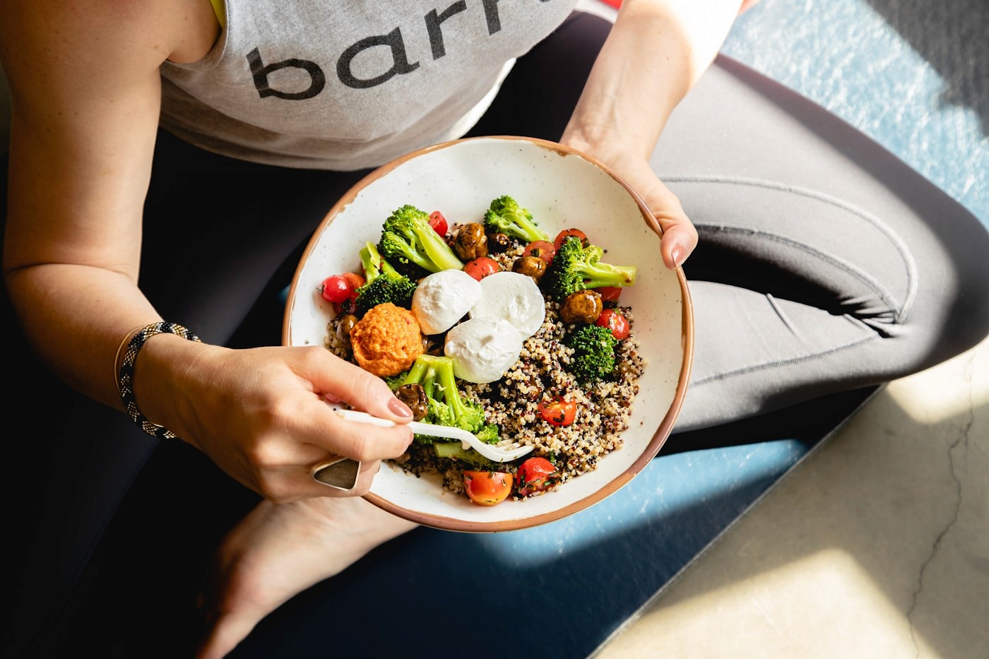A person holding a bowl of quinoa, roasted vegetables, and egg — a reminder that the body still needs nourishment even when hunger is quiet on a GLP-1.