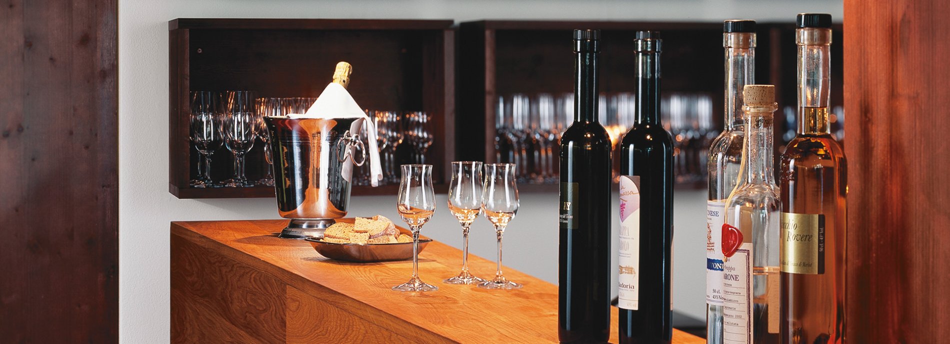 Weinbar mit Weinflaschen, Weingläsern, Sektkühler und Holztisch. Weinverkostung.
